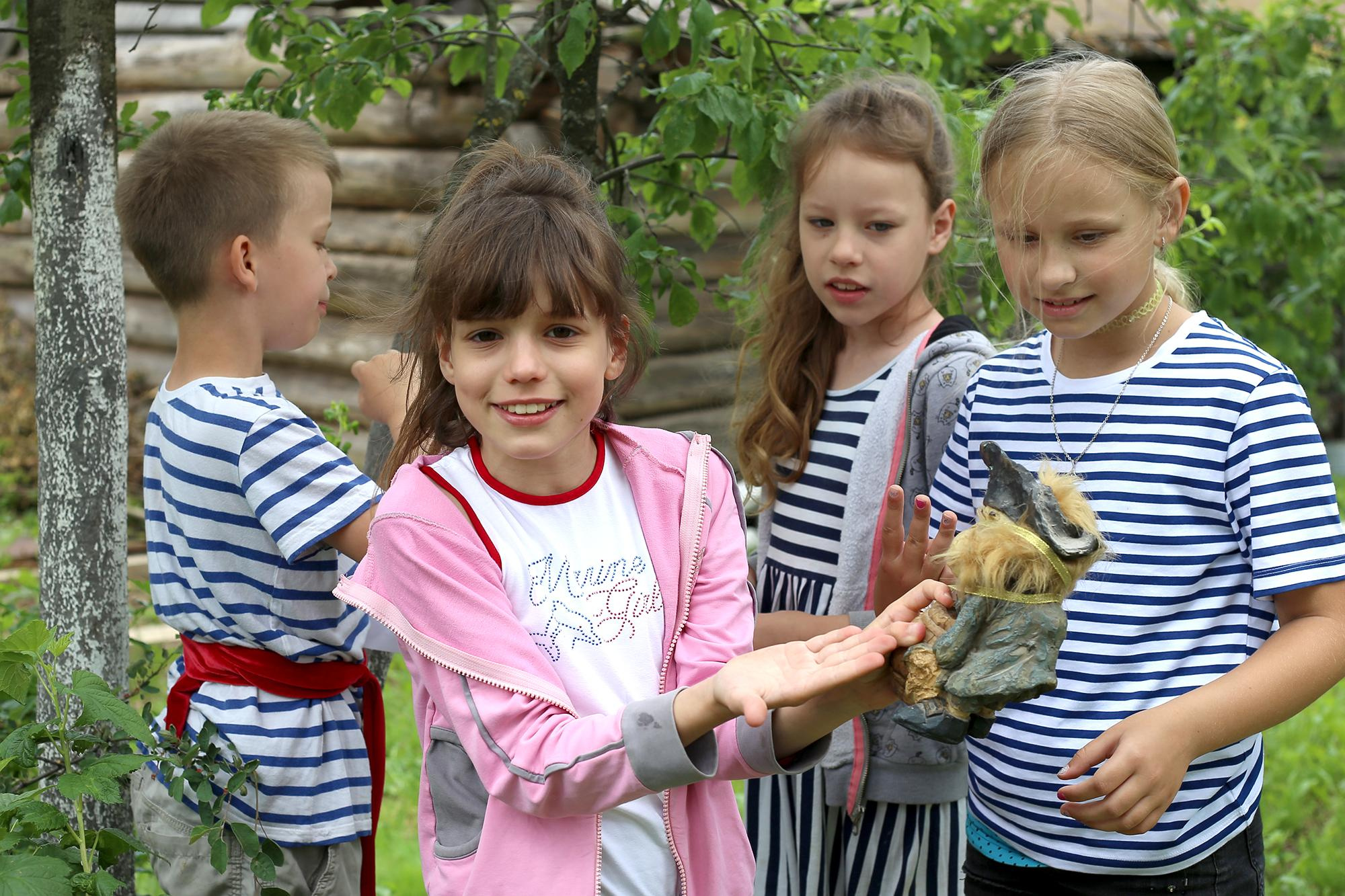 смешная темноволосая девочка в розовой байке показывает обезьяну