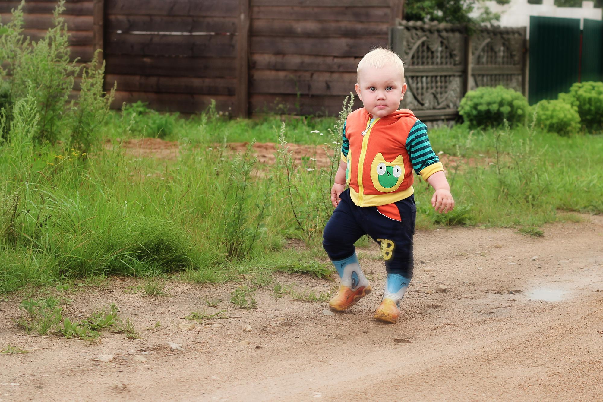 малыш в резиновых сапогах ходит по лужам