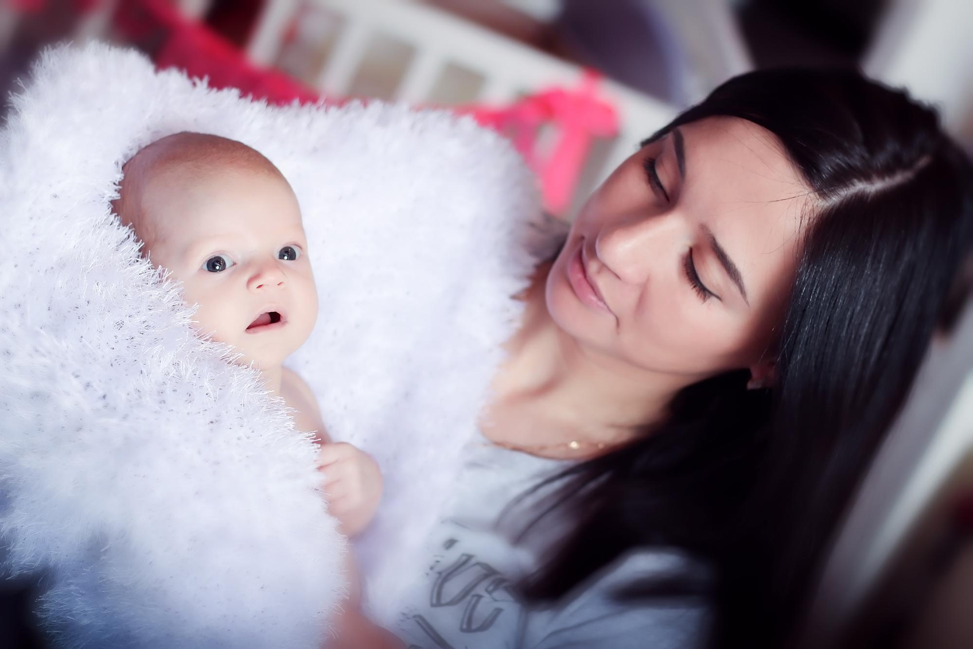 черноволосая мама держит на руках младенца