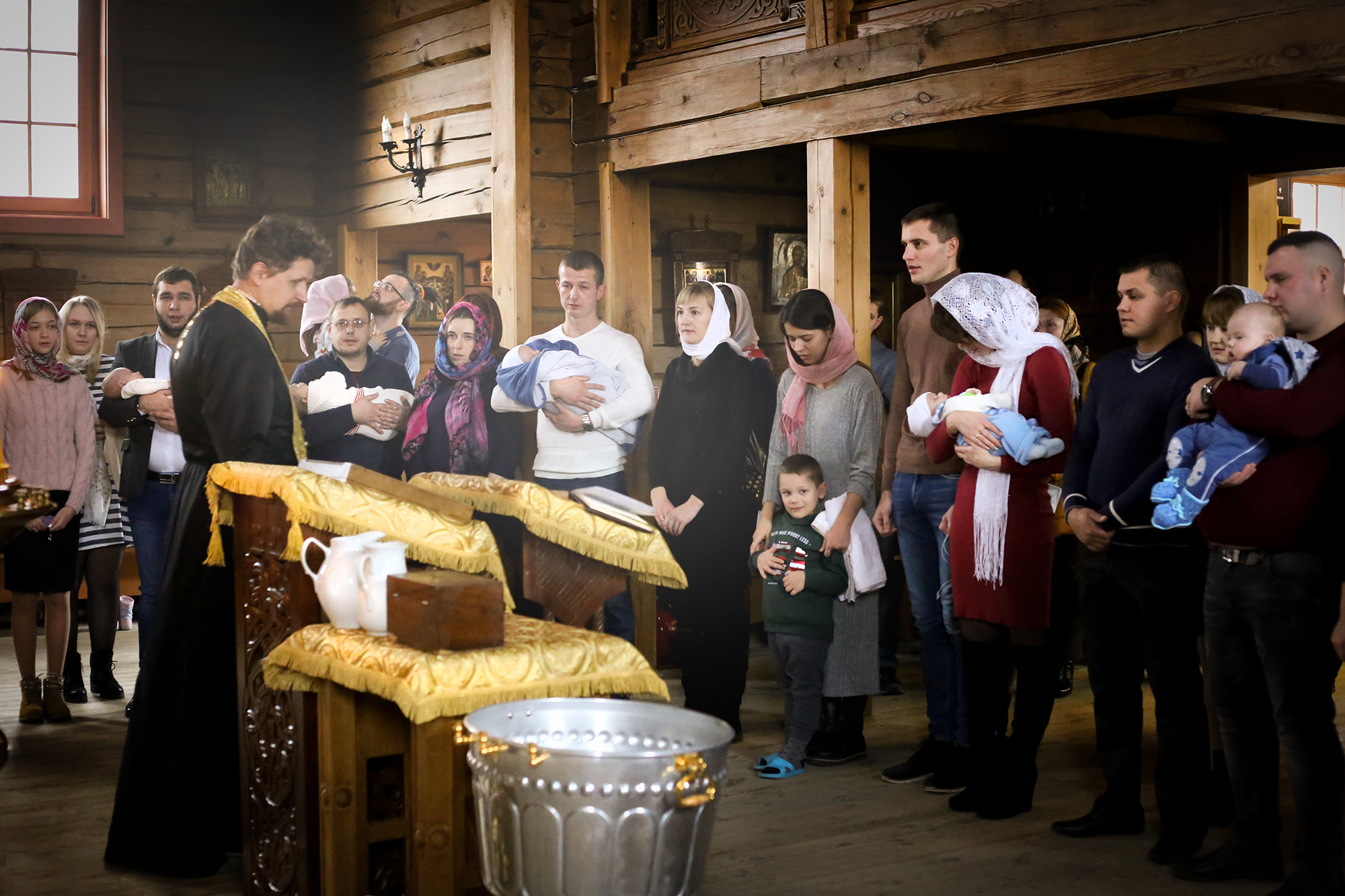 служба в деревянной церкви во время таинства крещения
