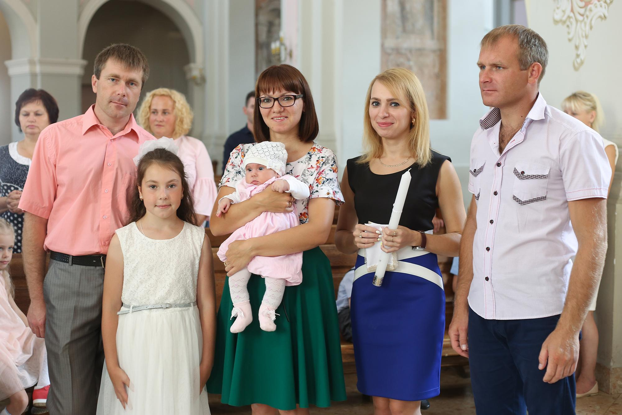 семья католиков на службе крестят третьего ребенка