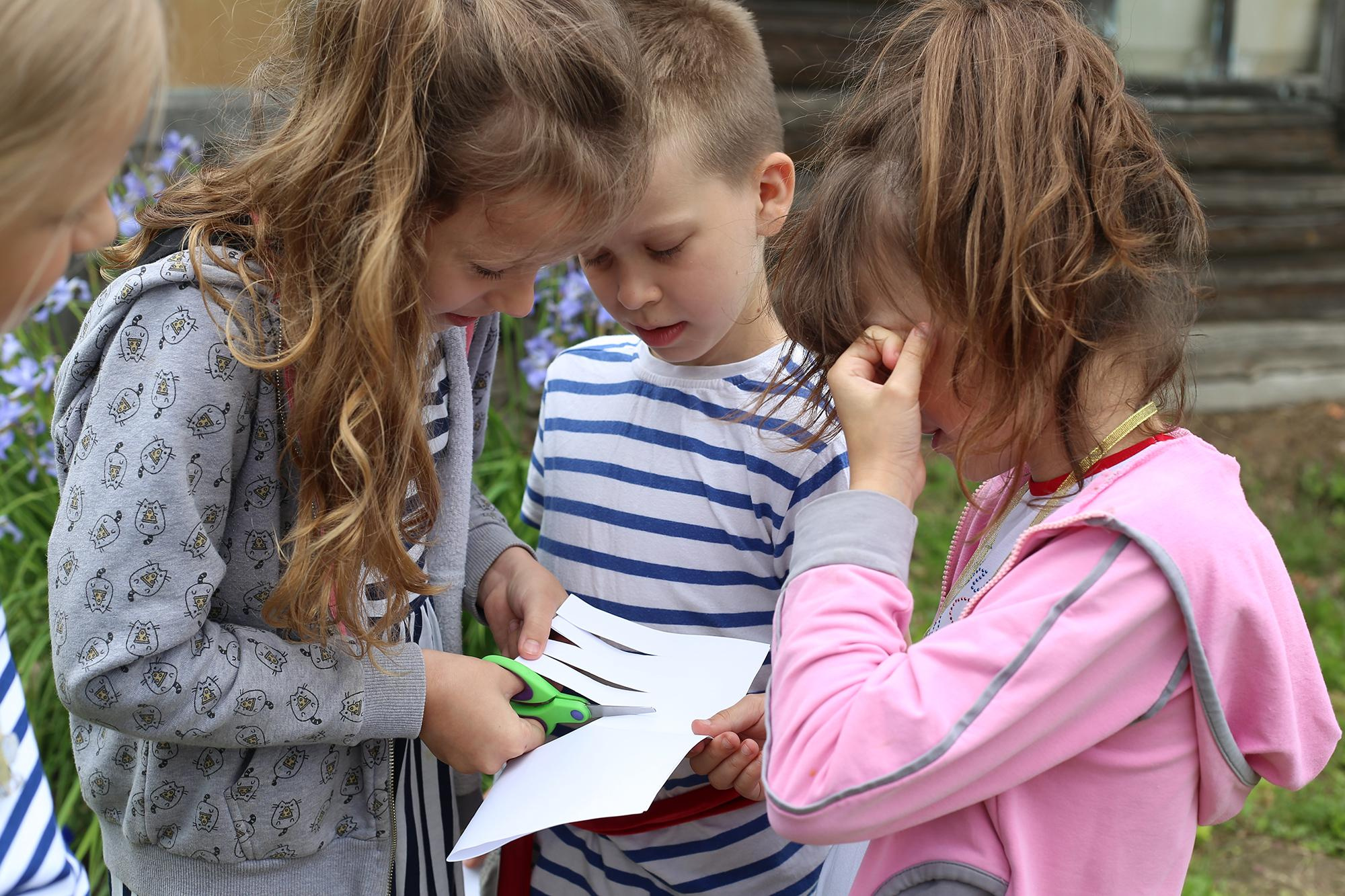 девочка с длинными волосами показывает фокус с бумагой