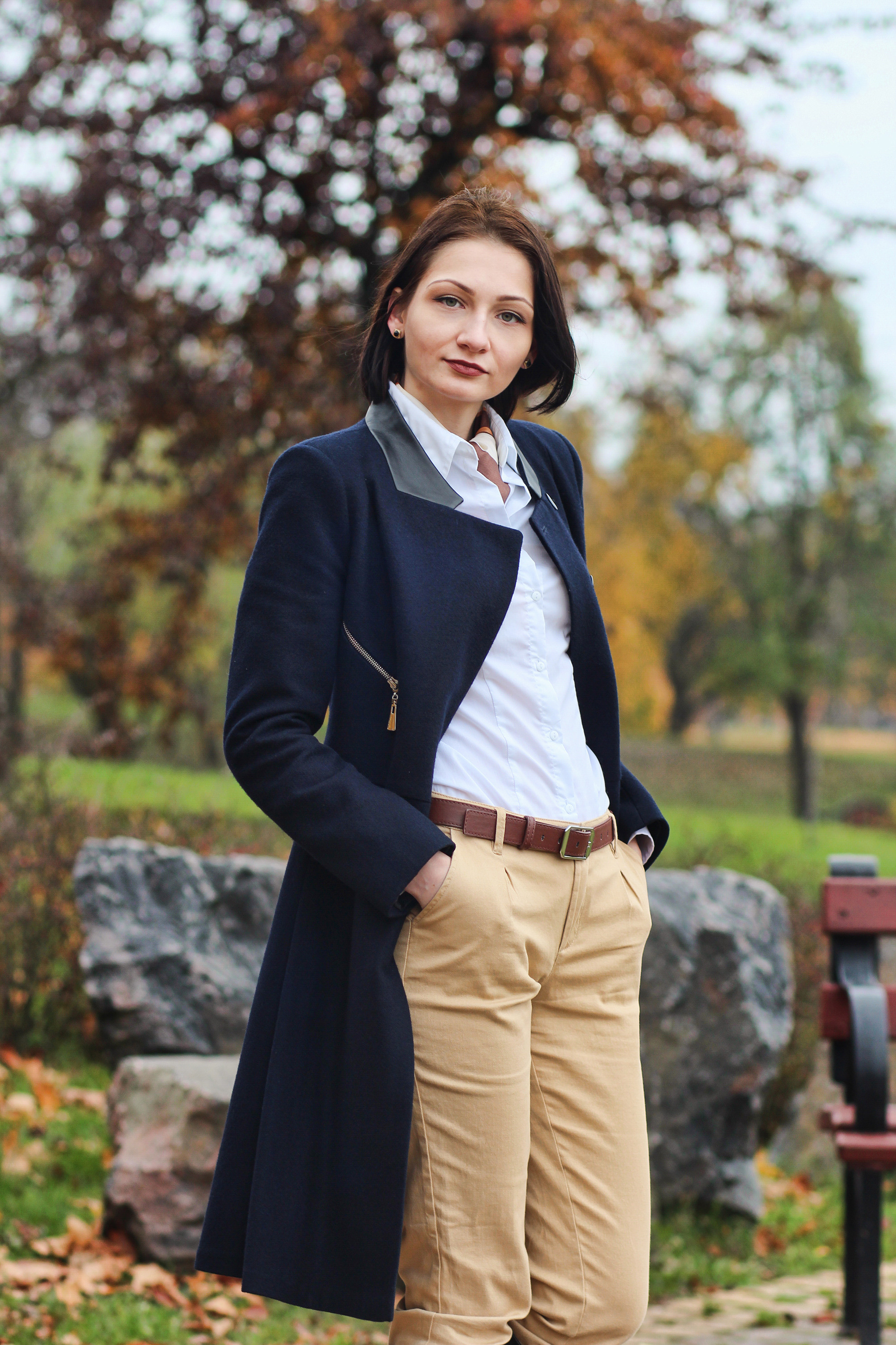 девушка в пальто засунула руки в карманы в Лошицком парке