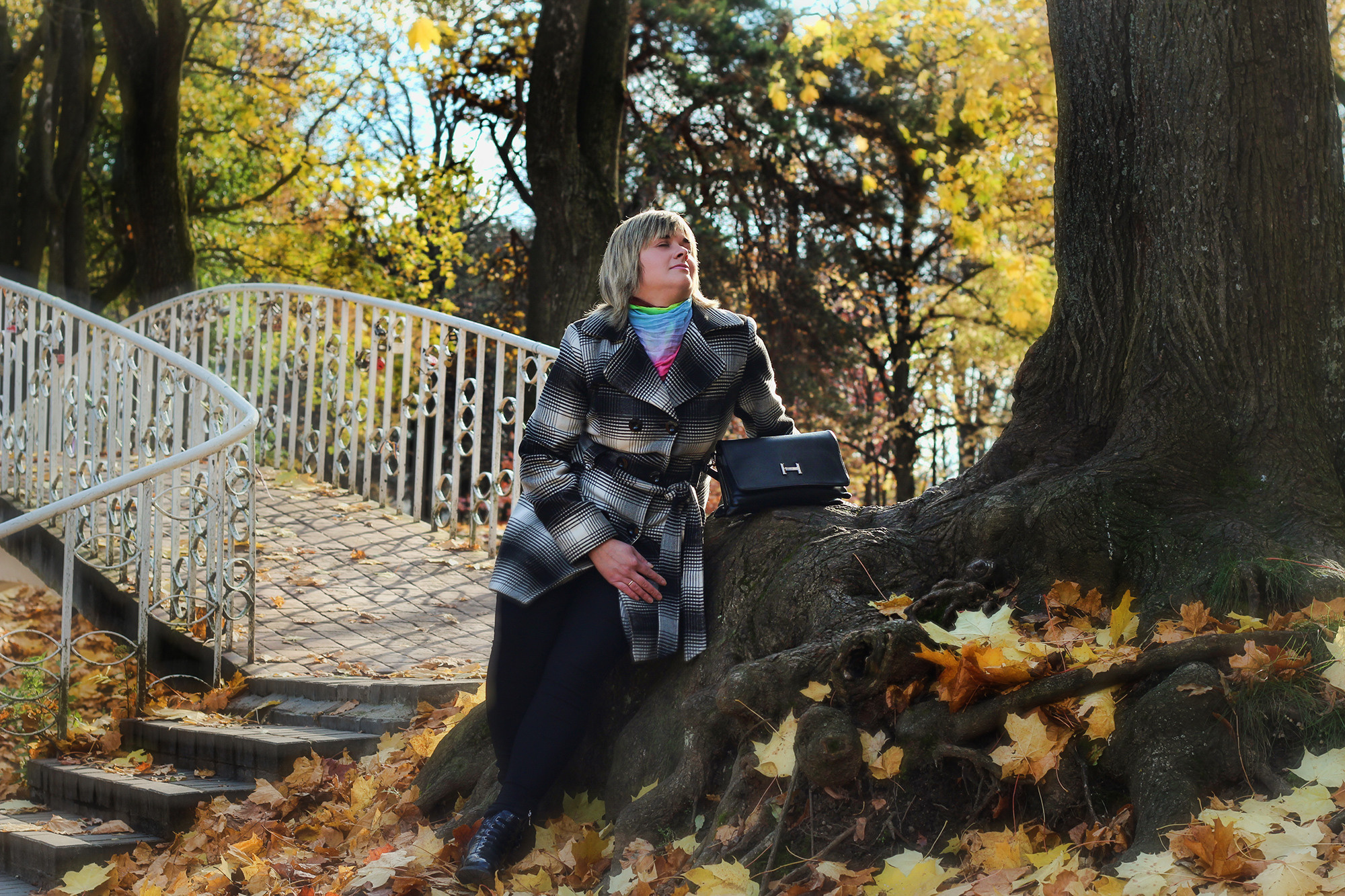 девушка сидит под деревом возле красивого мостика