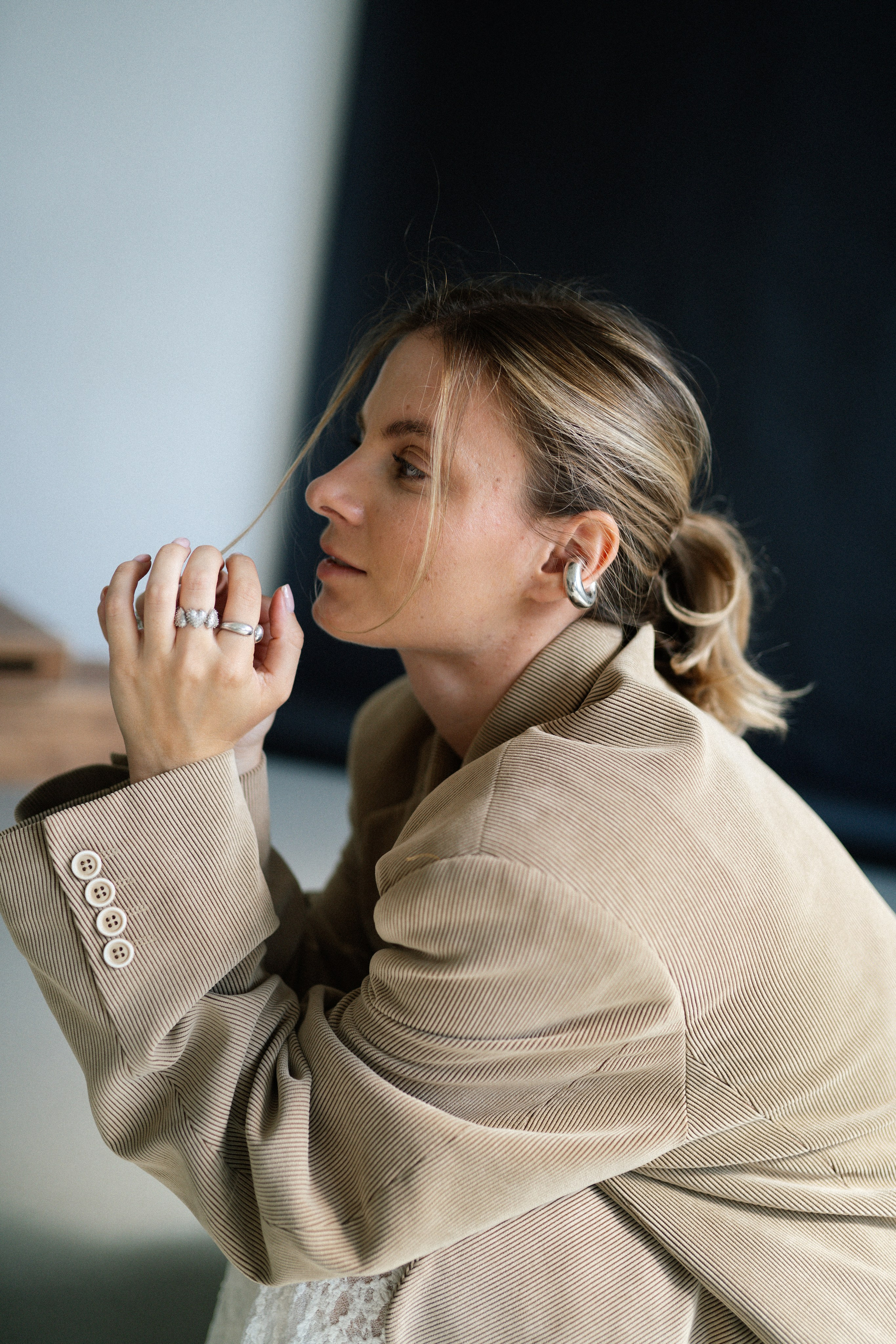 Портрет модели в бежевом жакете с крупными украшениями, стильная поза и детали на студийной фотосессии в Санкт-Петербурге