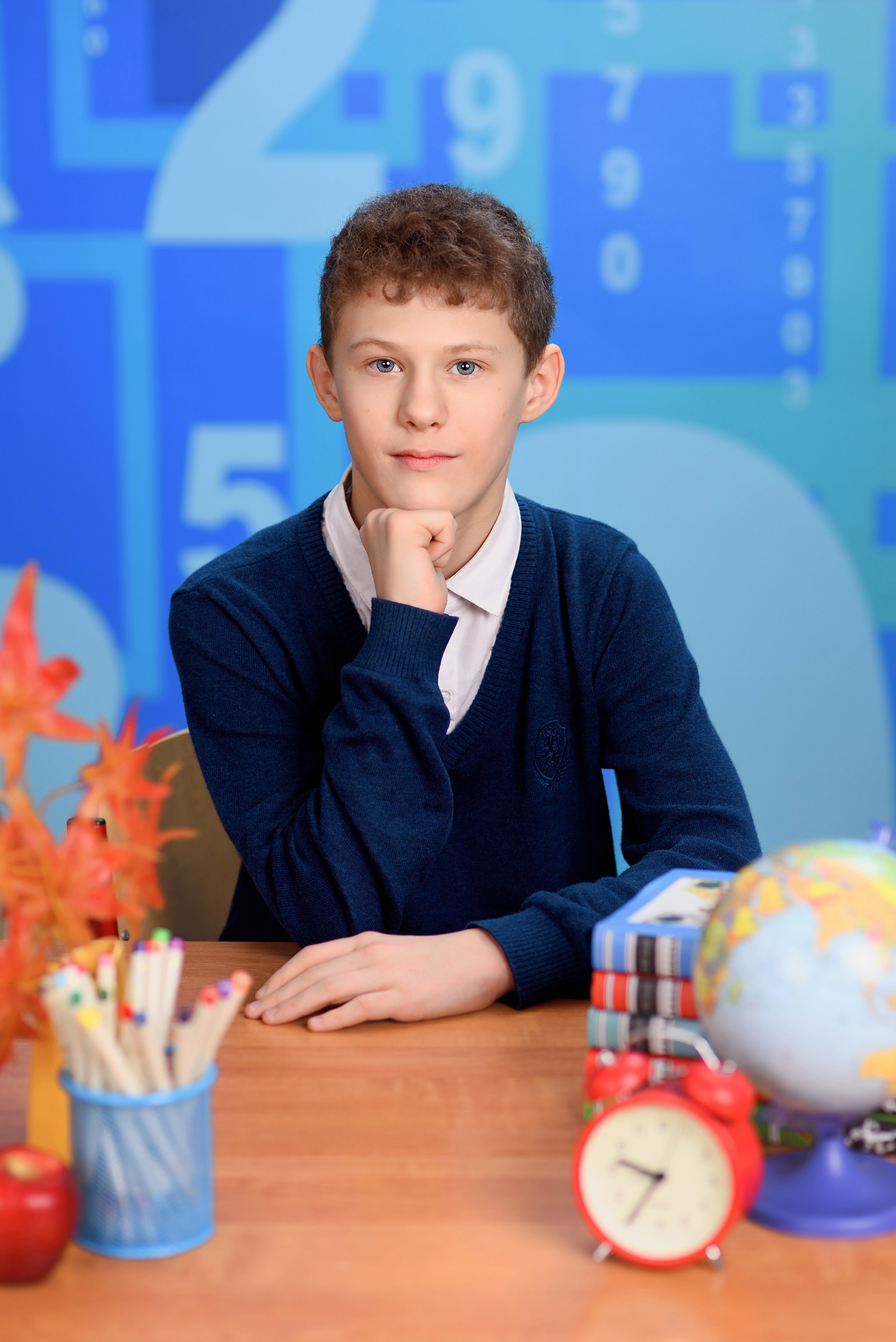 Классический портрет школьника за школьной партой с кулачком под подбородком.