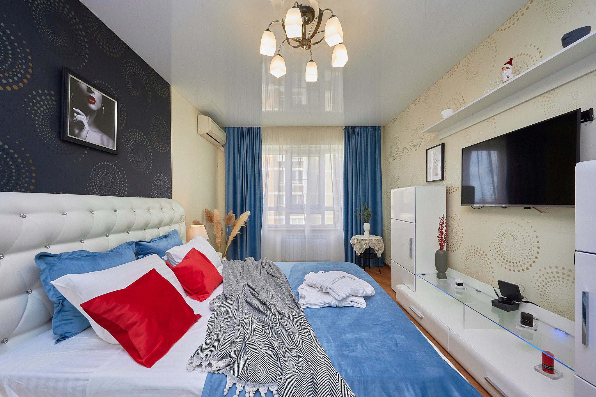 комната голубые шторы  белая кровать белая тумбочка под телевизор 