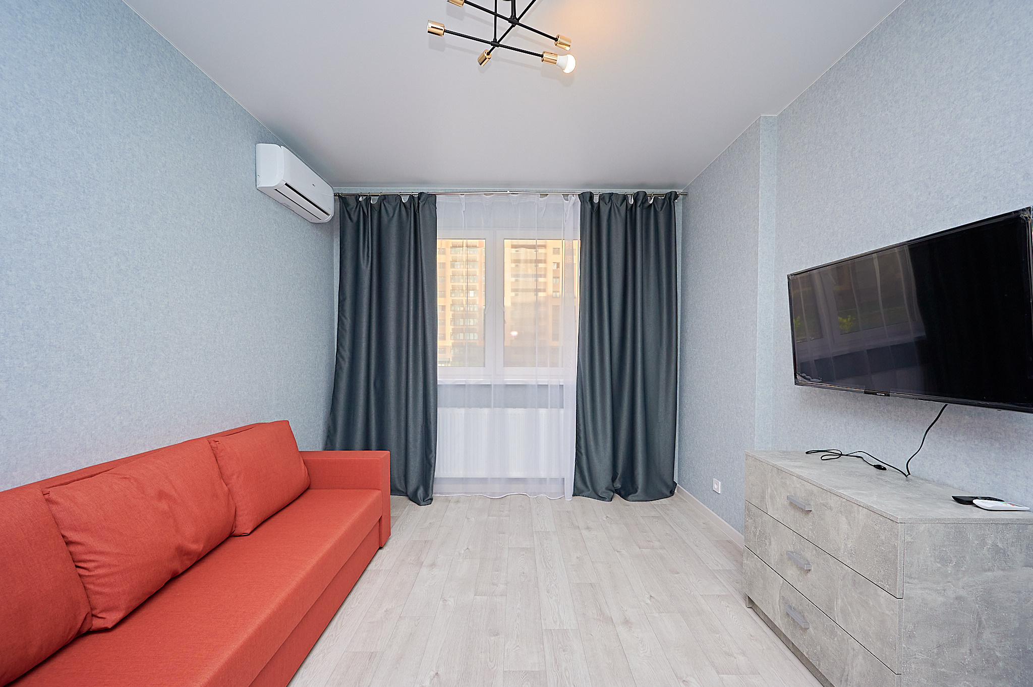 гостиная красный диван серые шторы серая тумбочка 