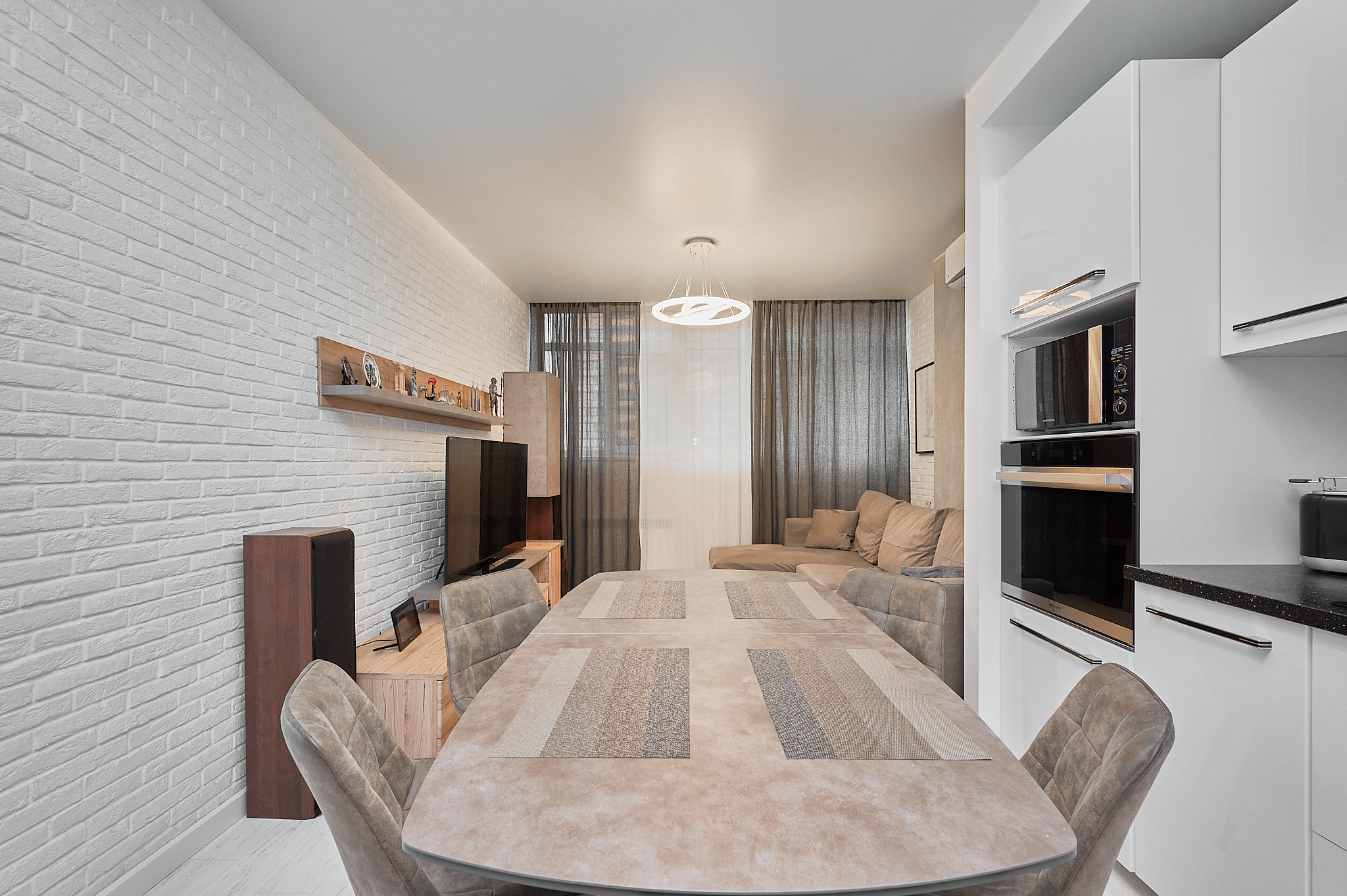 кухня  большой кухонный мраморный стол с белыми шкафчиками каменной белой стеной 