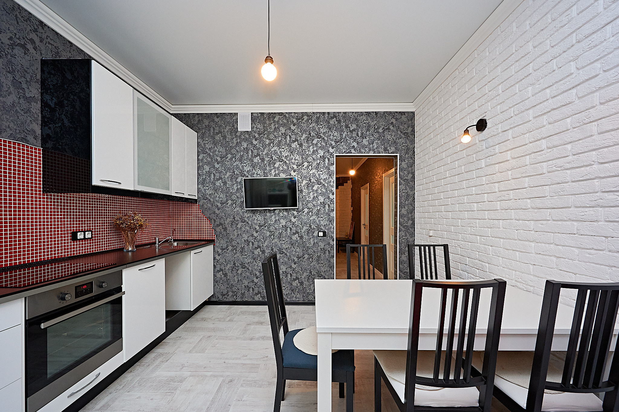 кухня  белая каменная стена  белый кухонный стол белые шкафчики  черные стулья 