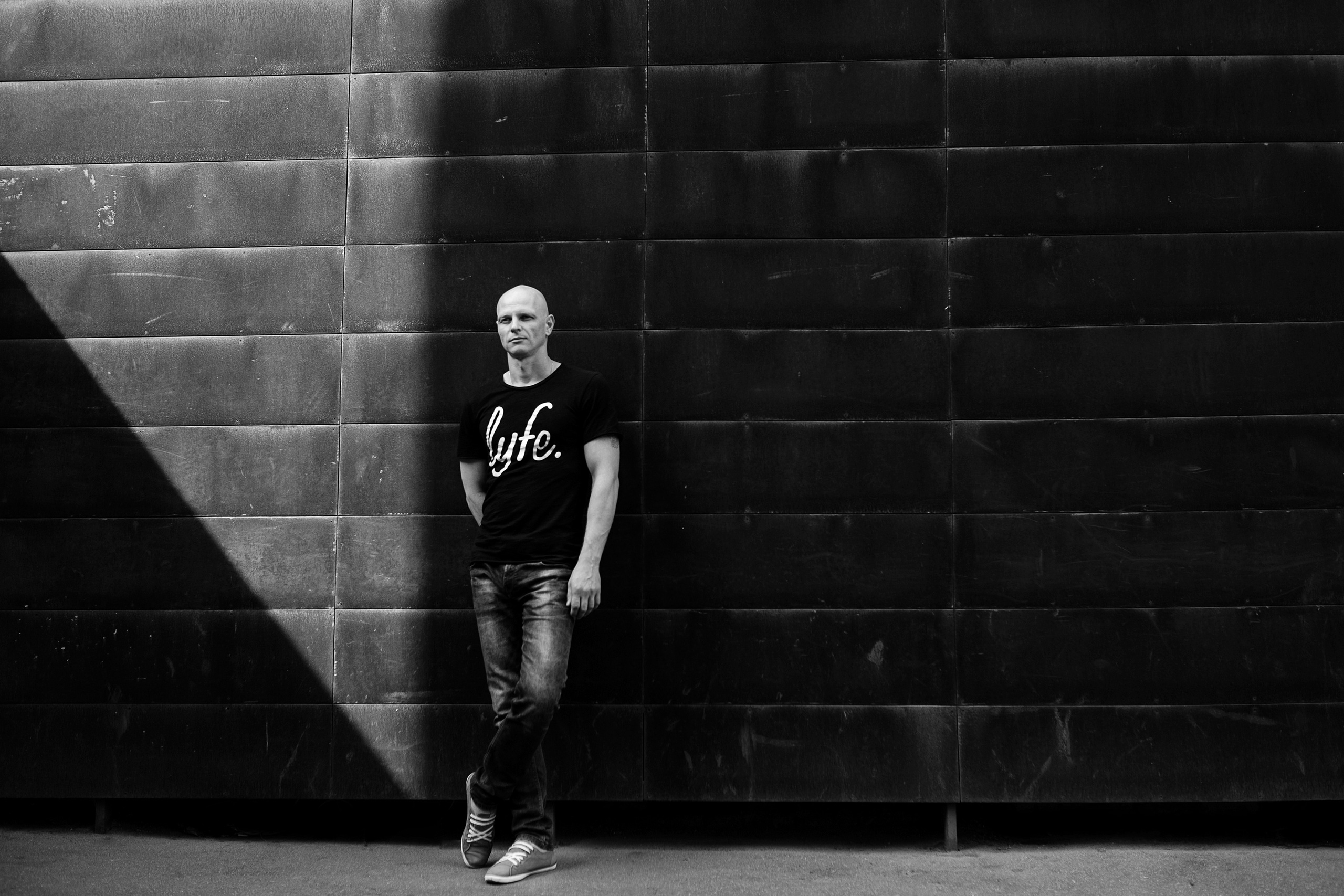 Парень позирует фотографу на фоне графичной чёрной стены