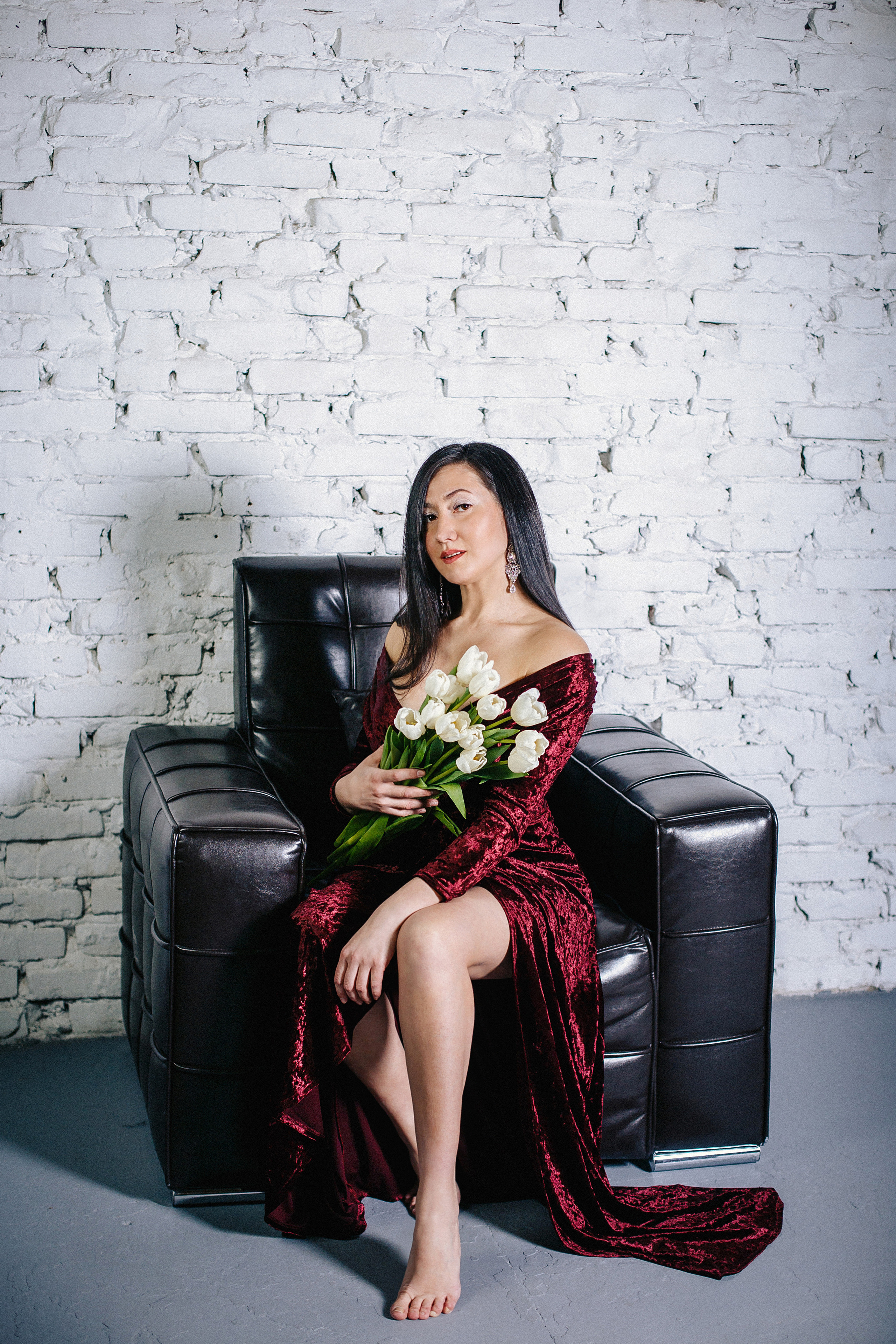 студийная фотосессия для девушки с цветами в длинном платье бордо