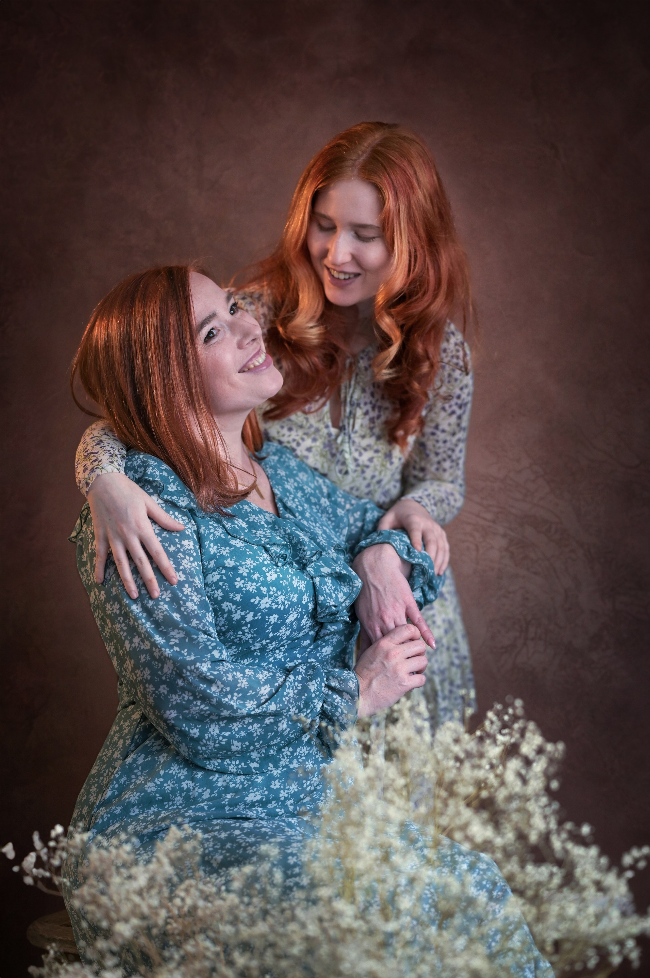 Студийный портрет двух рыжеволосых девушек с улыбкой разговаривающих между собой