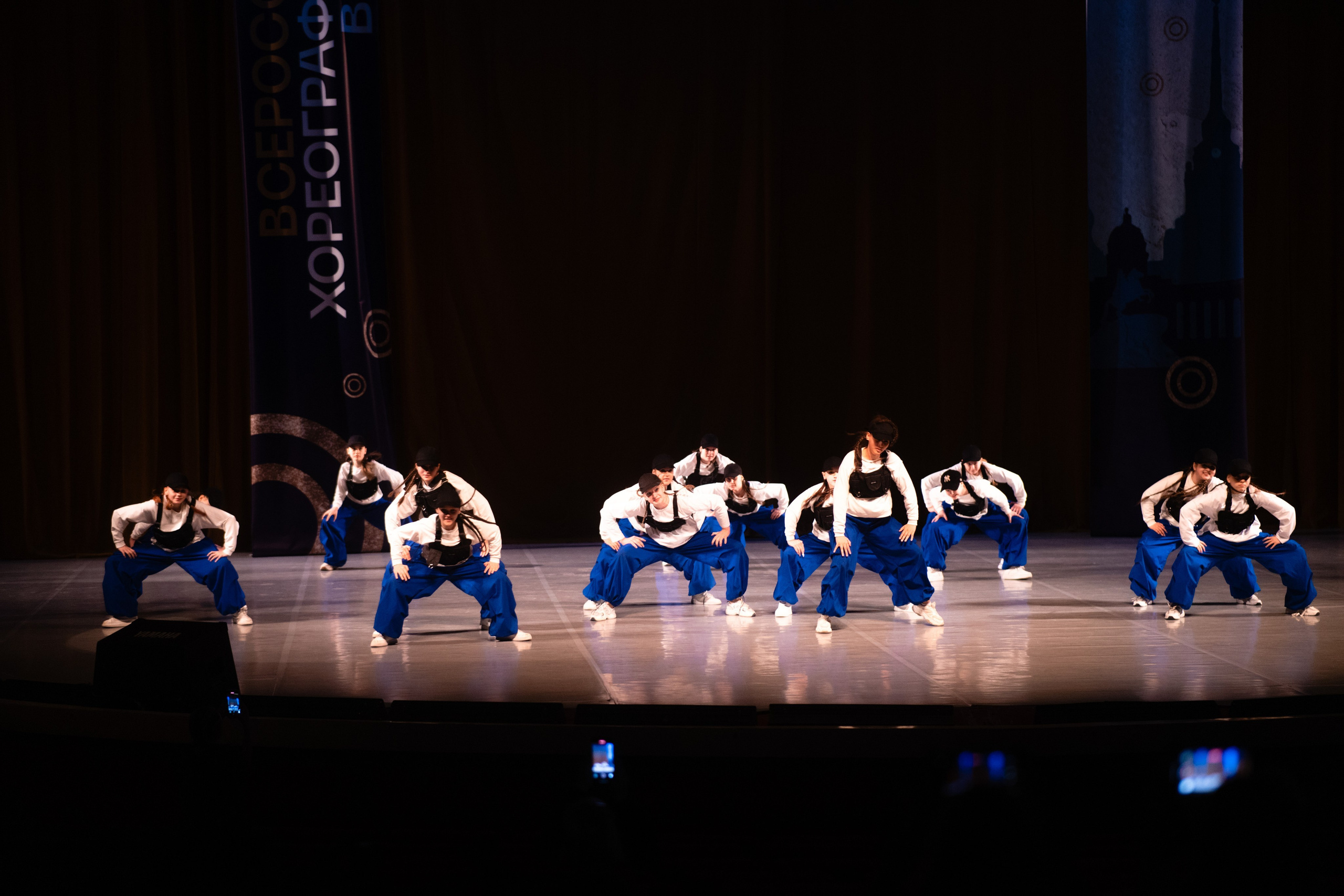 Панорама сцены и части зала: группа танцовщиц исполняет синхронное движение в СПб.