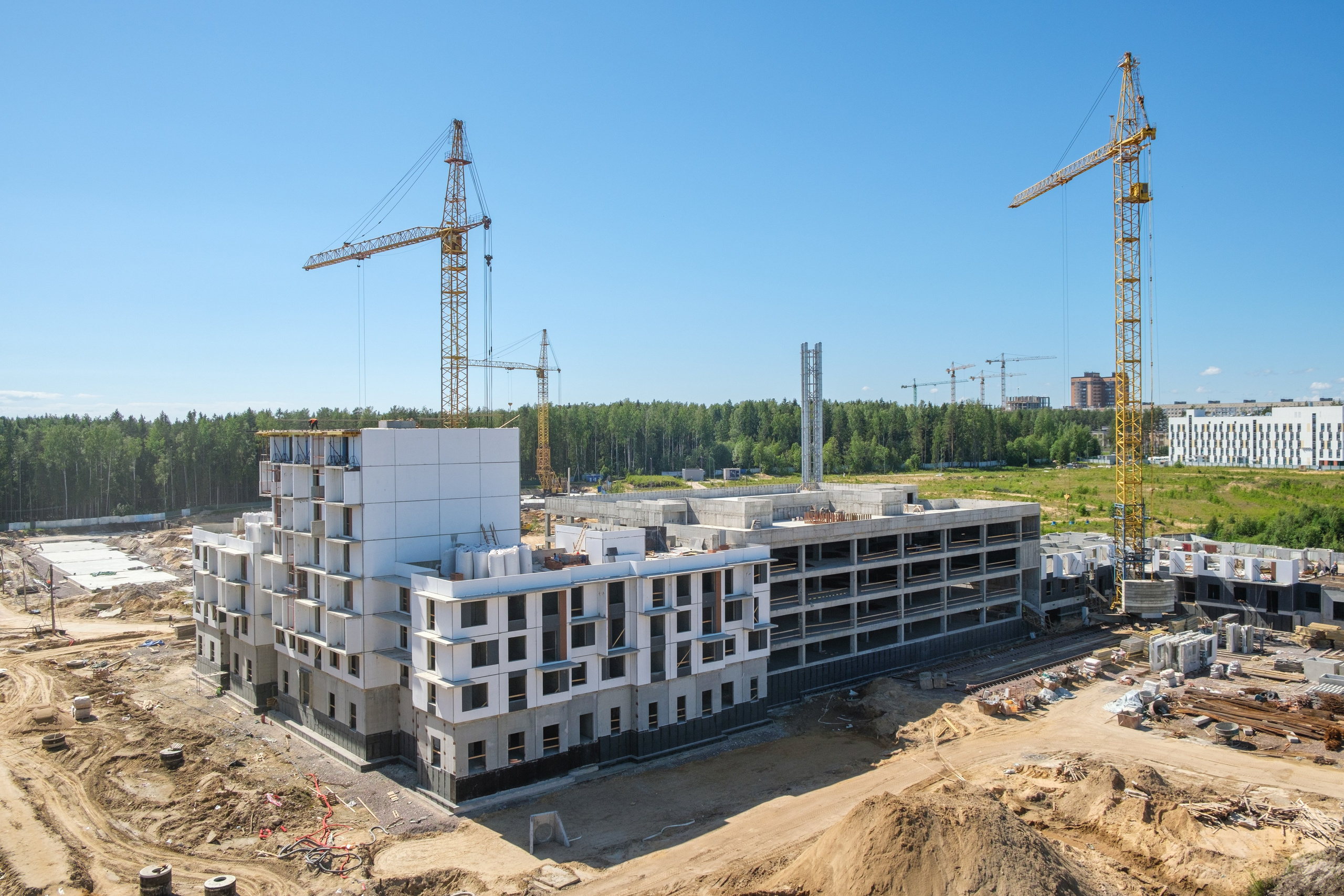 На изображении представлен вид на строительную площадку, где возводятся многоквартирные жилые дома.