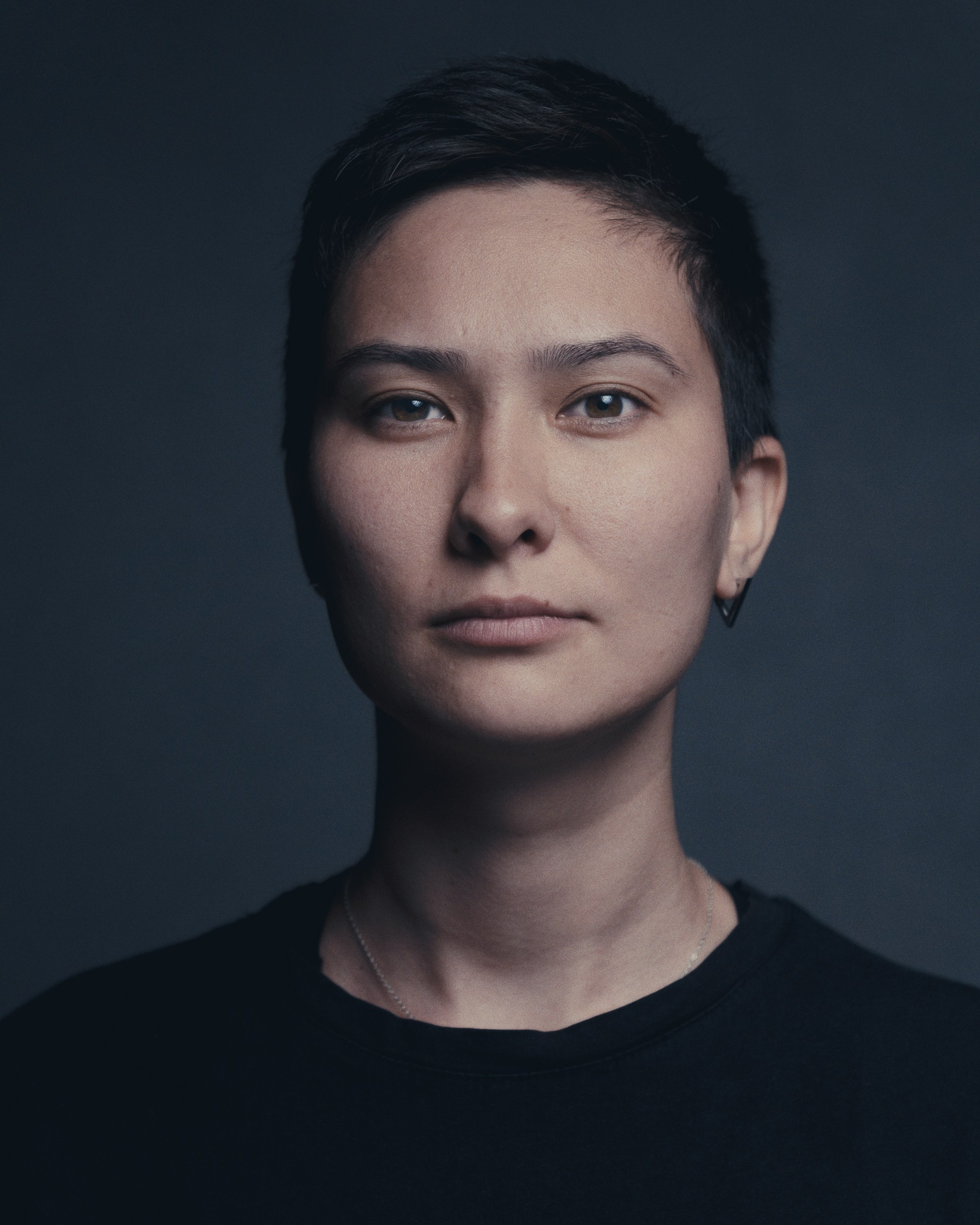 Студийный портрет человека на тёмном фоне с мягким боковым светом — минималистичная профессиональная портретная съёмка.