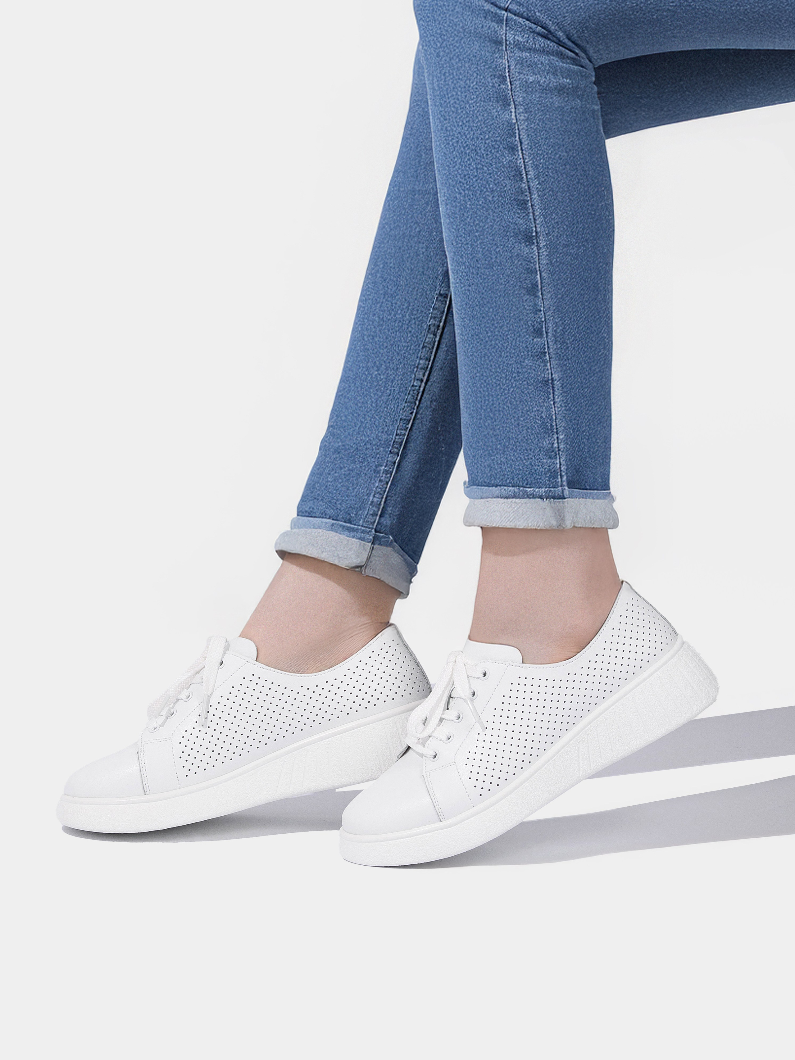 Белые летние кеды на ногах модели в джинсах