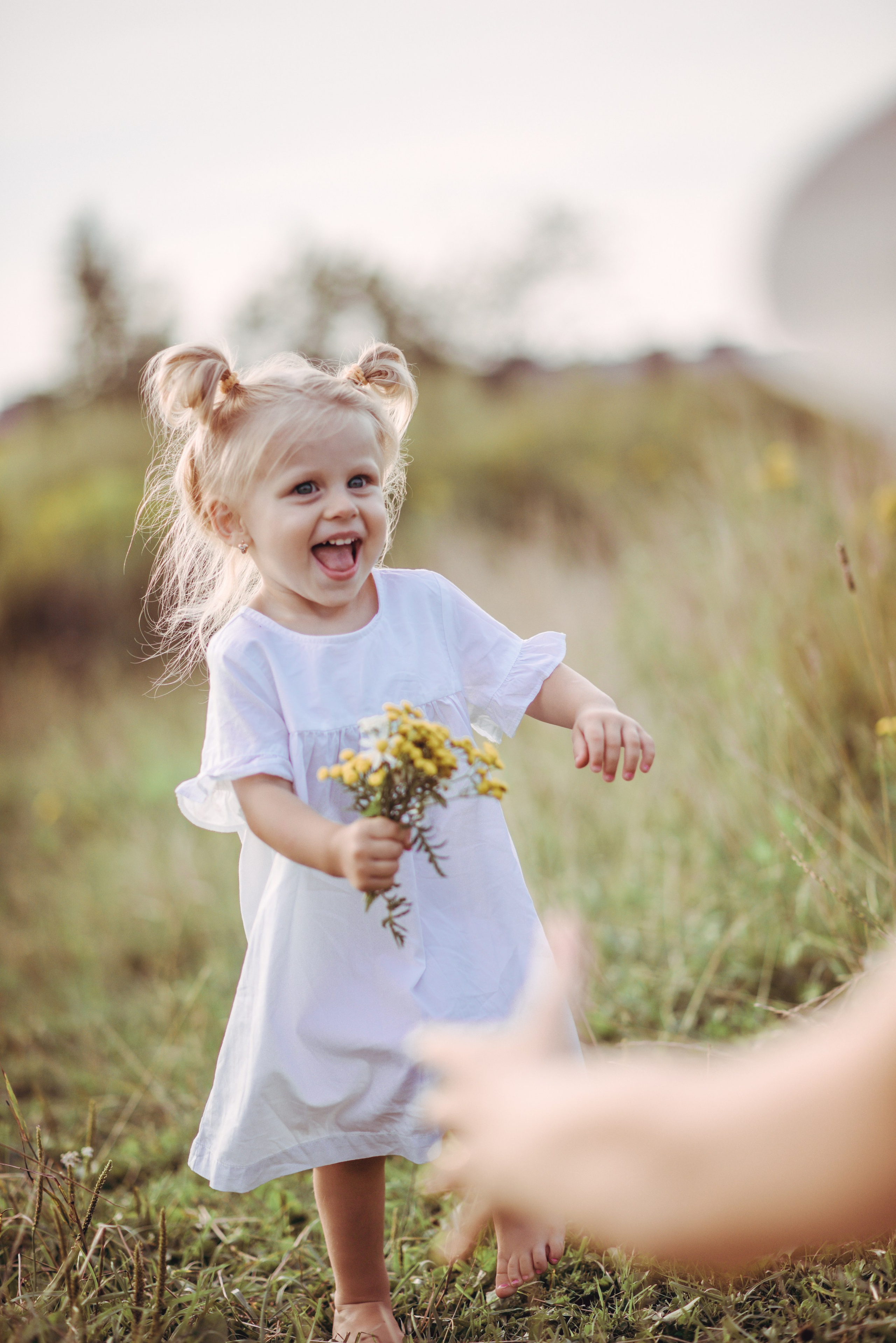 Little girl running in tall grass to her mother and smiling