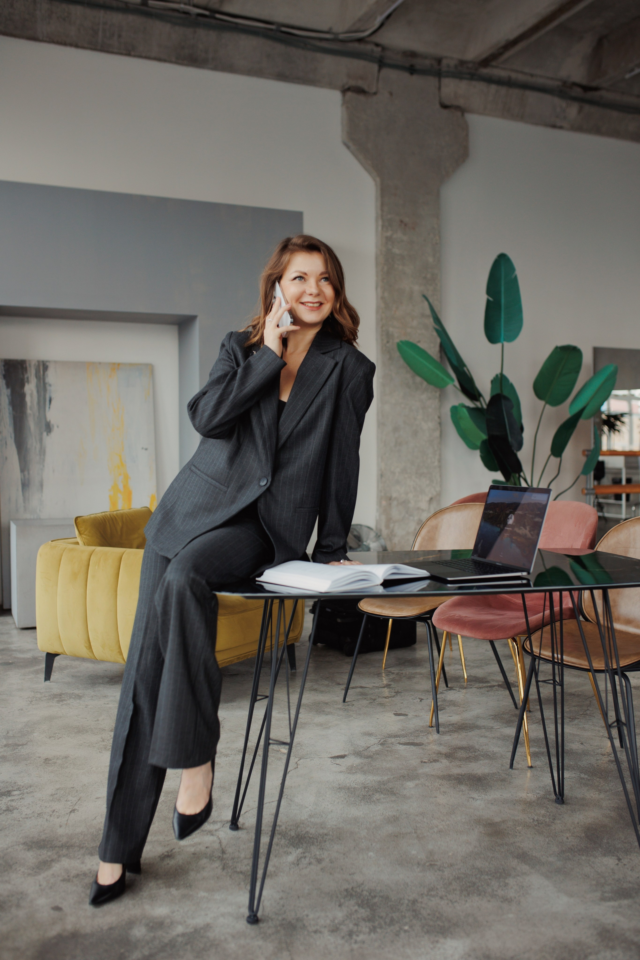 Девушка в деловом костюме в неформальной позе, облокотившись на стол.