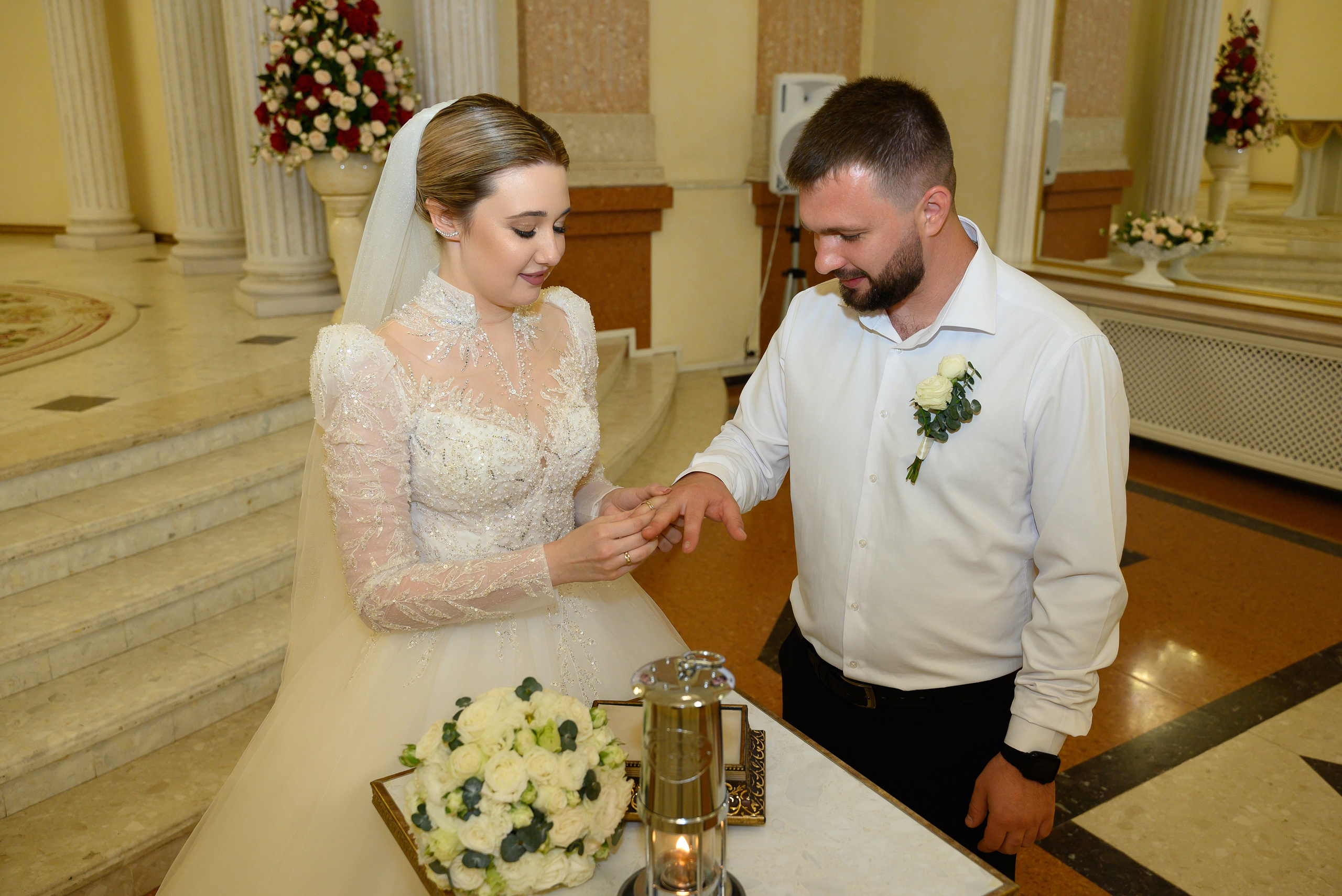 Невеста надевает кольцо на руку жениха.