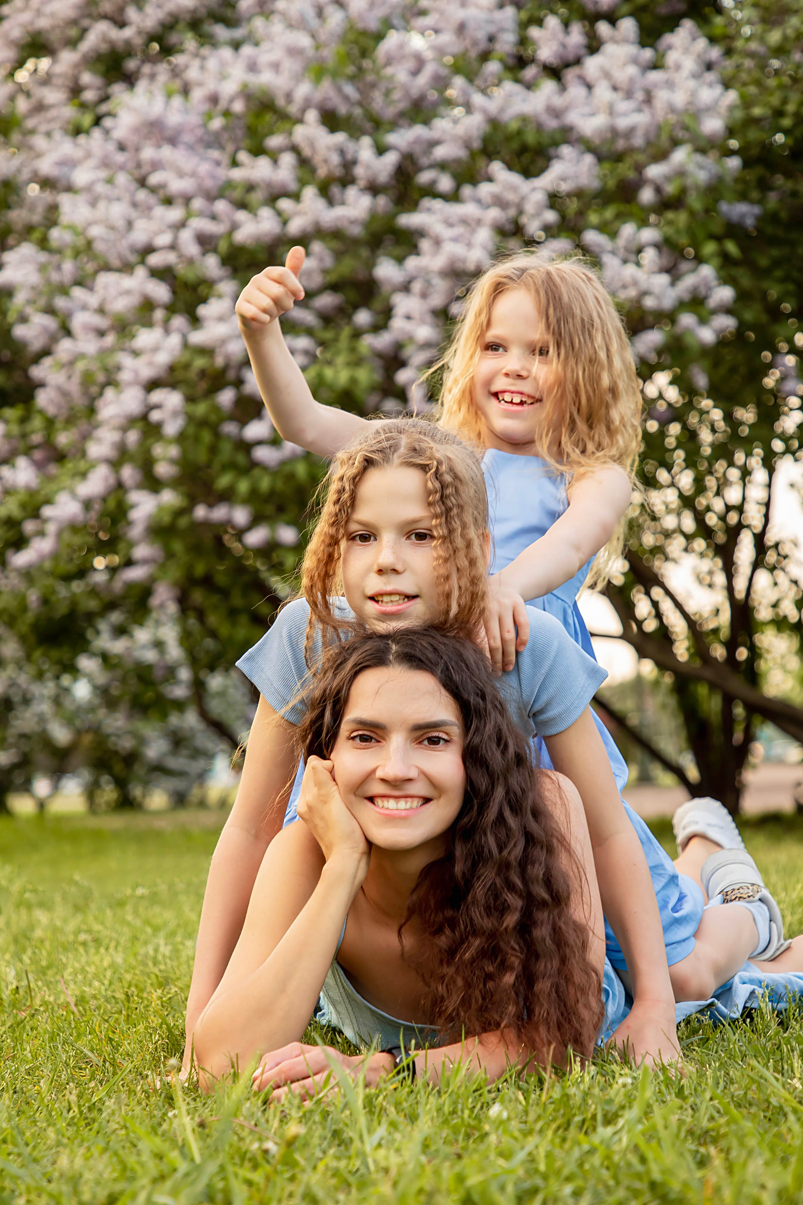 съемка на мамы и двух дочерей с длинными волосами и в платьях на фоне сирени