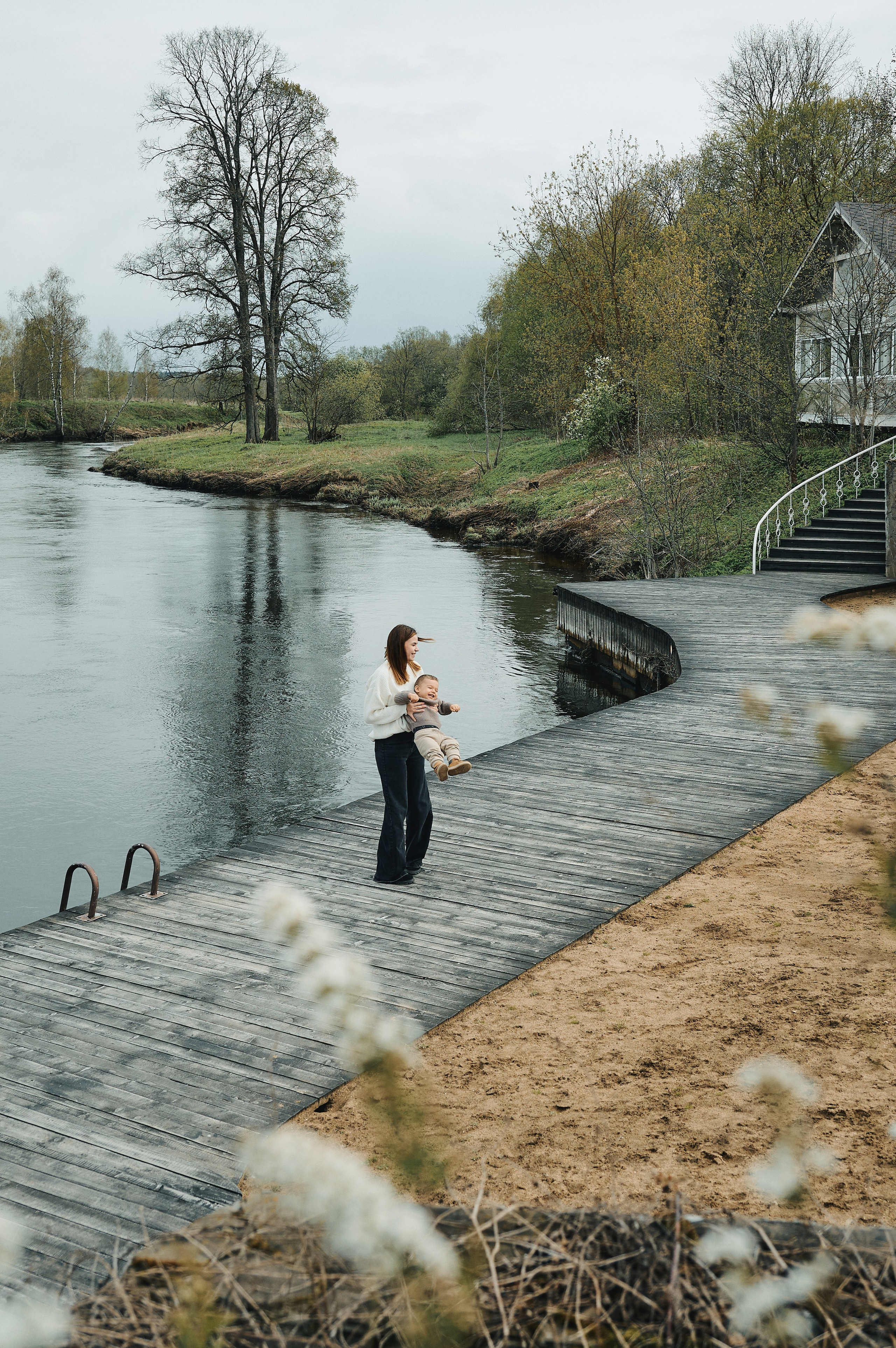 мама играет с ребёнком на деревянной набережной у реки, весенняя природа, спокойствие