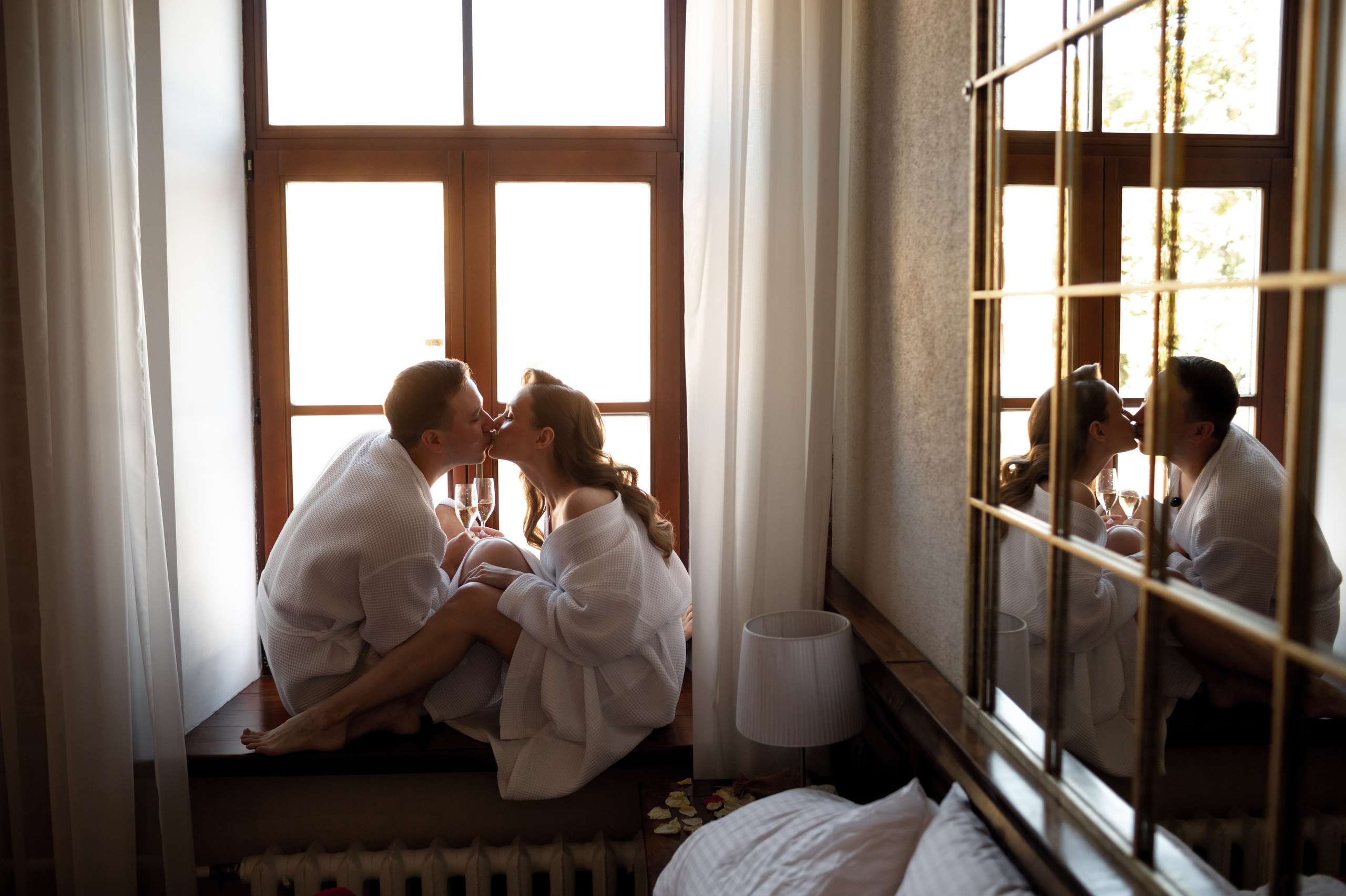 Утро жениха и невесты: молодожены в халатах на подоконнике с бокалами шампанского.