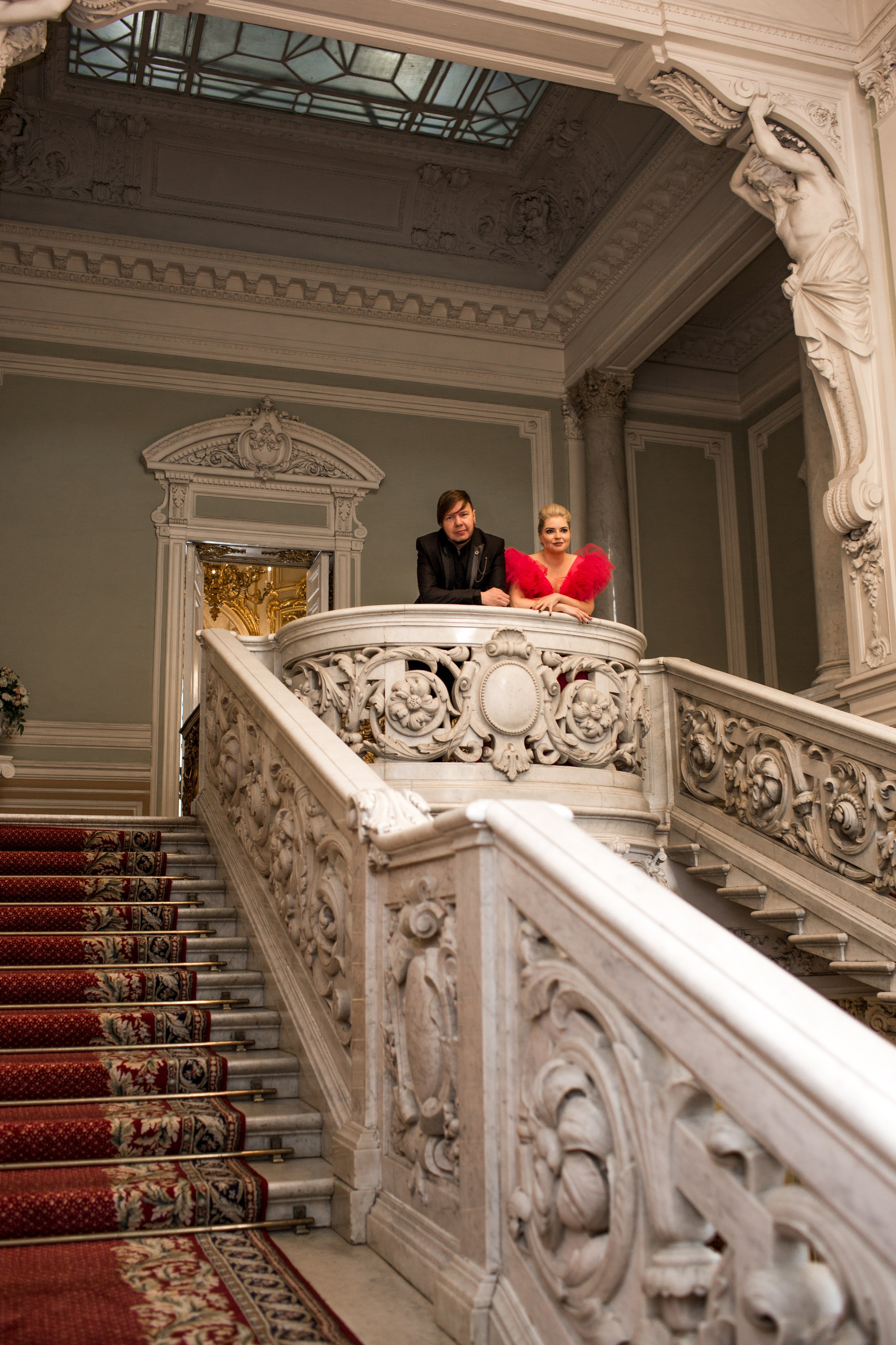 Молодожёны улыбаются друг другу на фоне городской классики