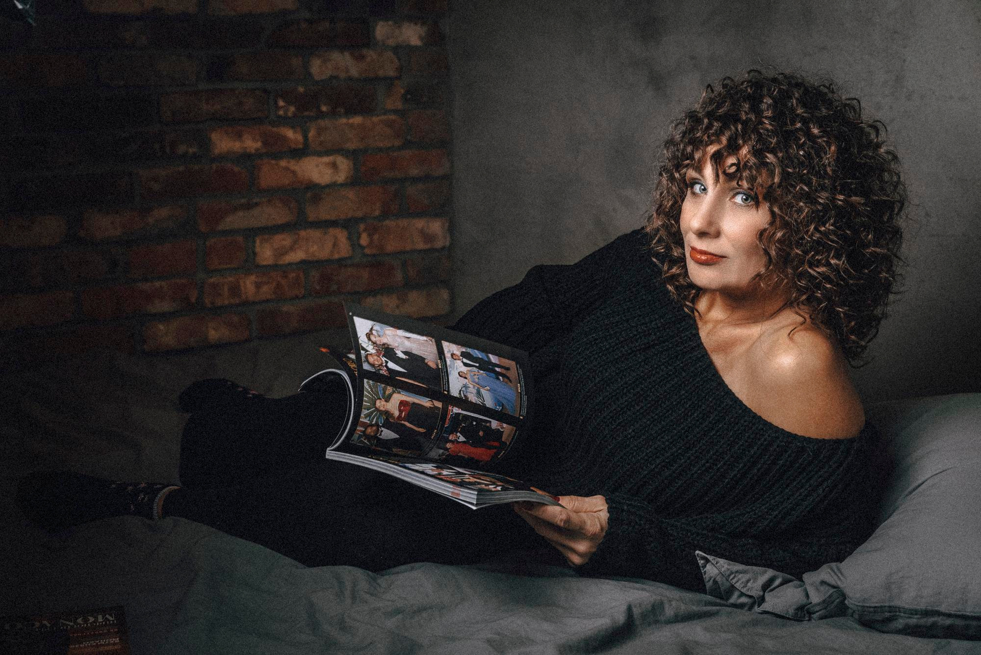 Портрет женщины которая лежит на кровати и читает журнал