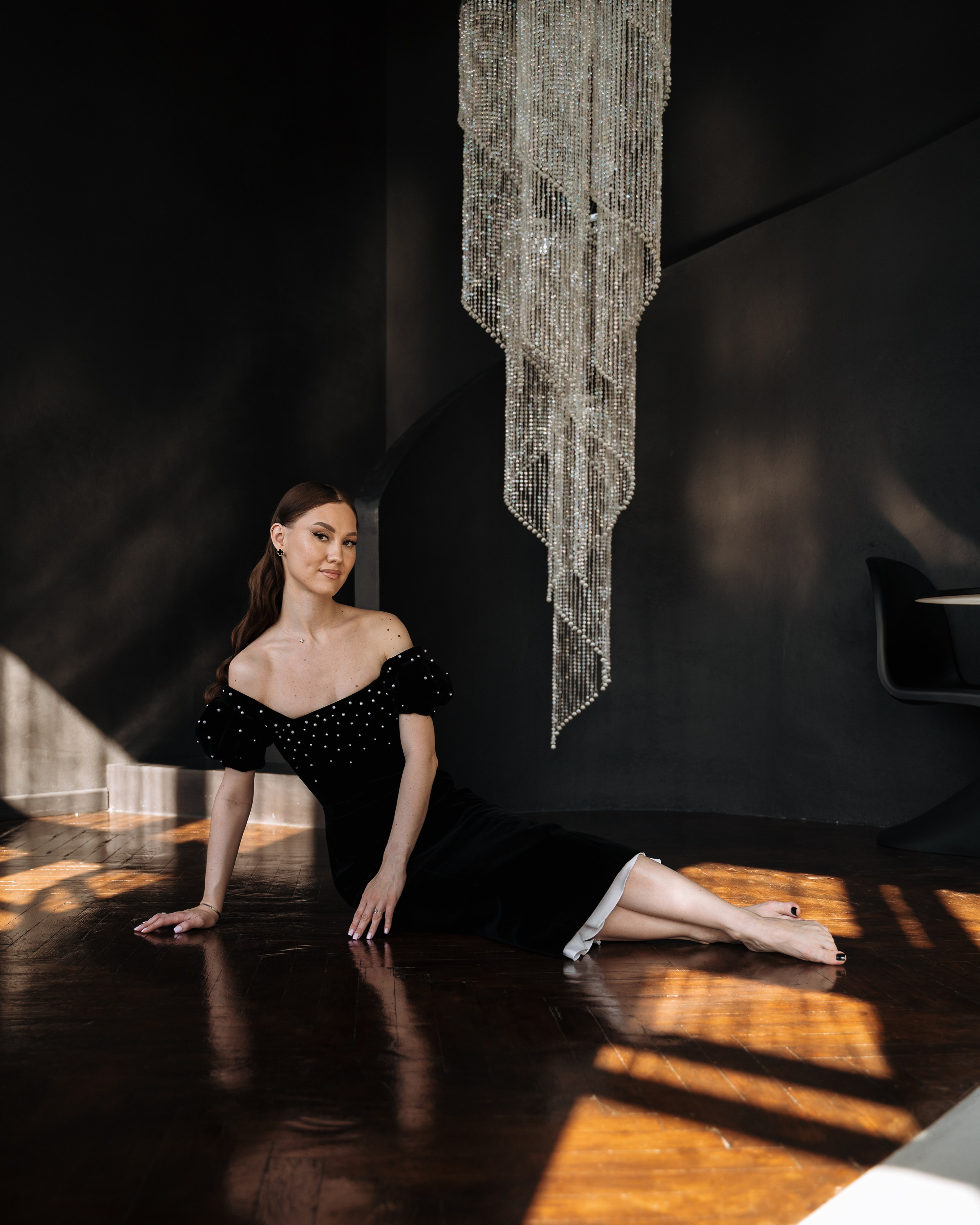 портретная фотосессия девушки в черном платье на темном фоне с люстрой