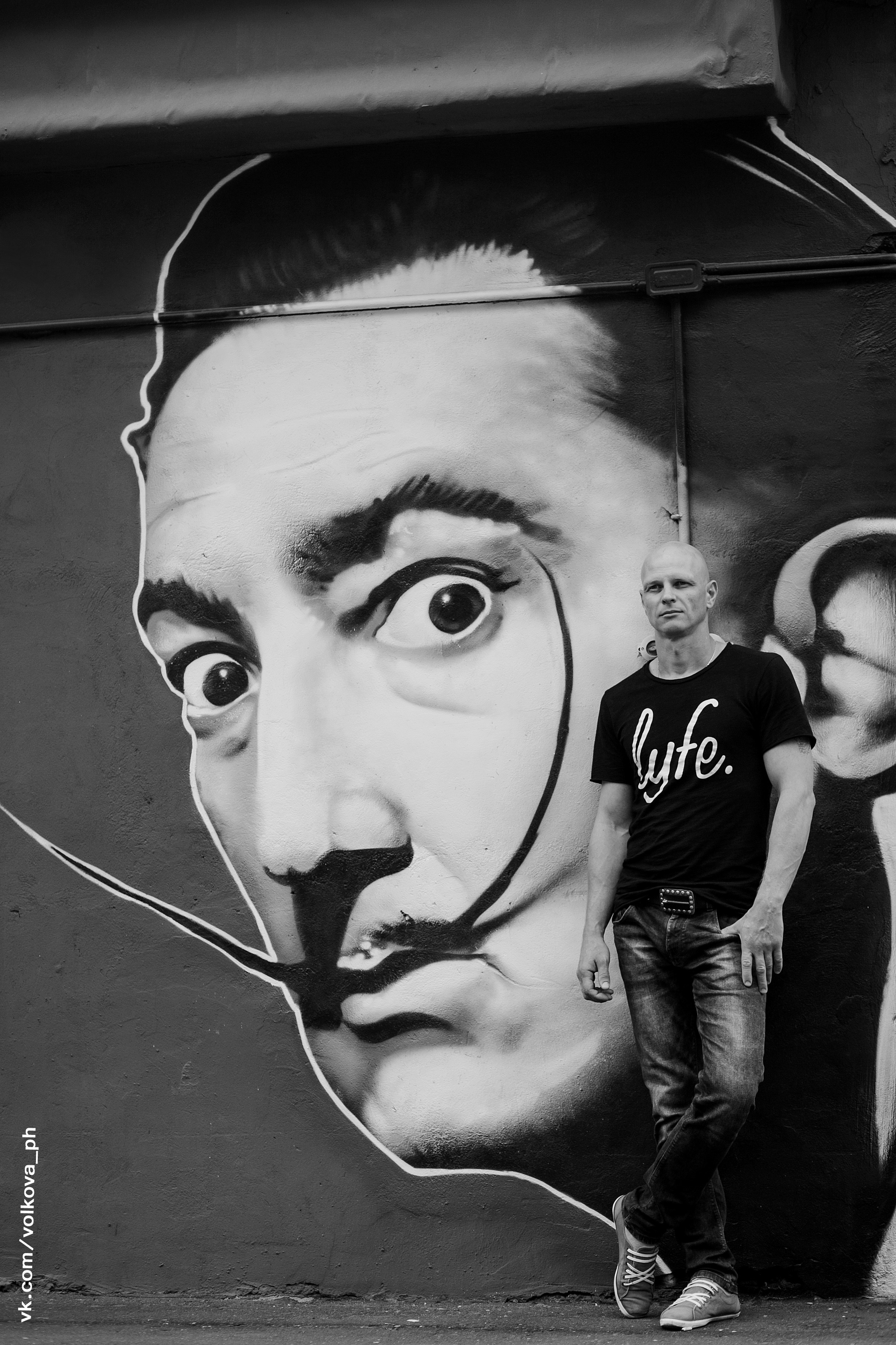 Стильный парень стоит у стены с портретом сальвадора дали