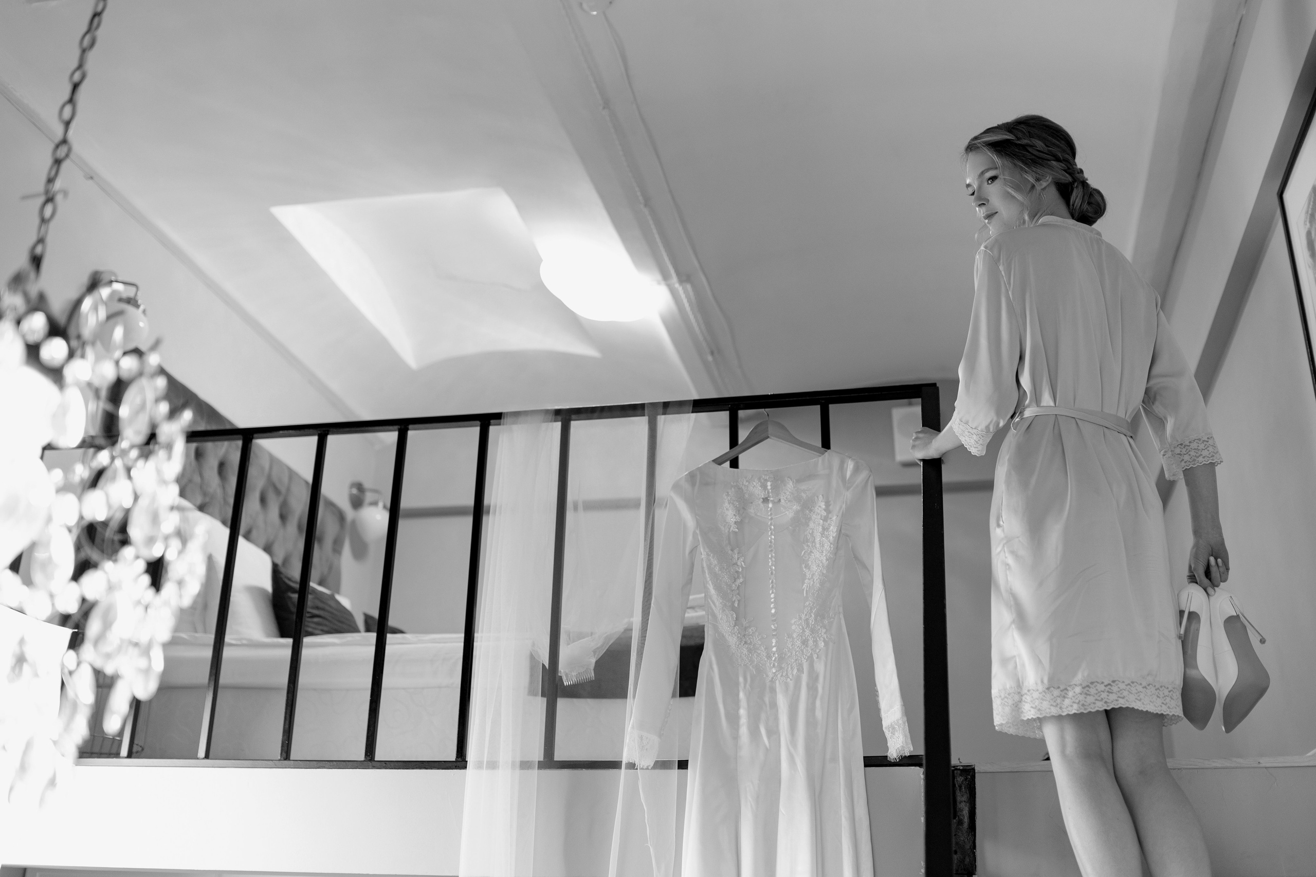 Невеста поднимается по лестнице с туфельками в руках.