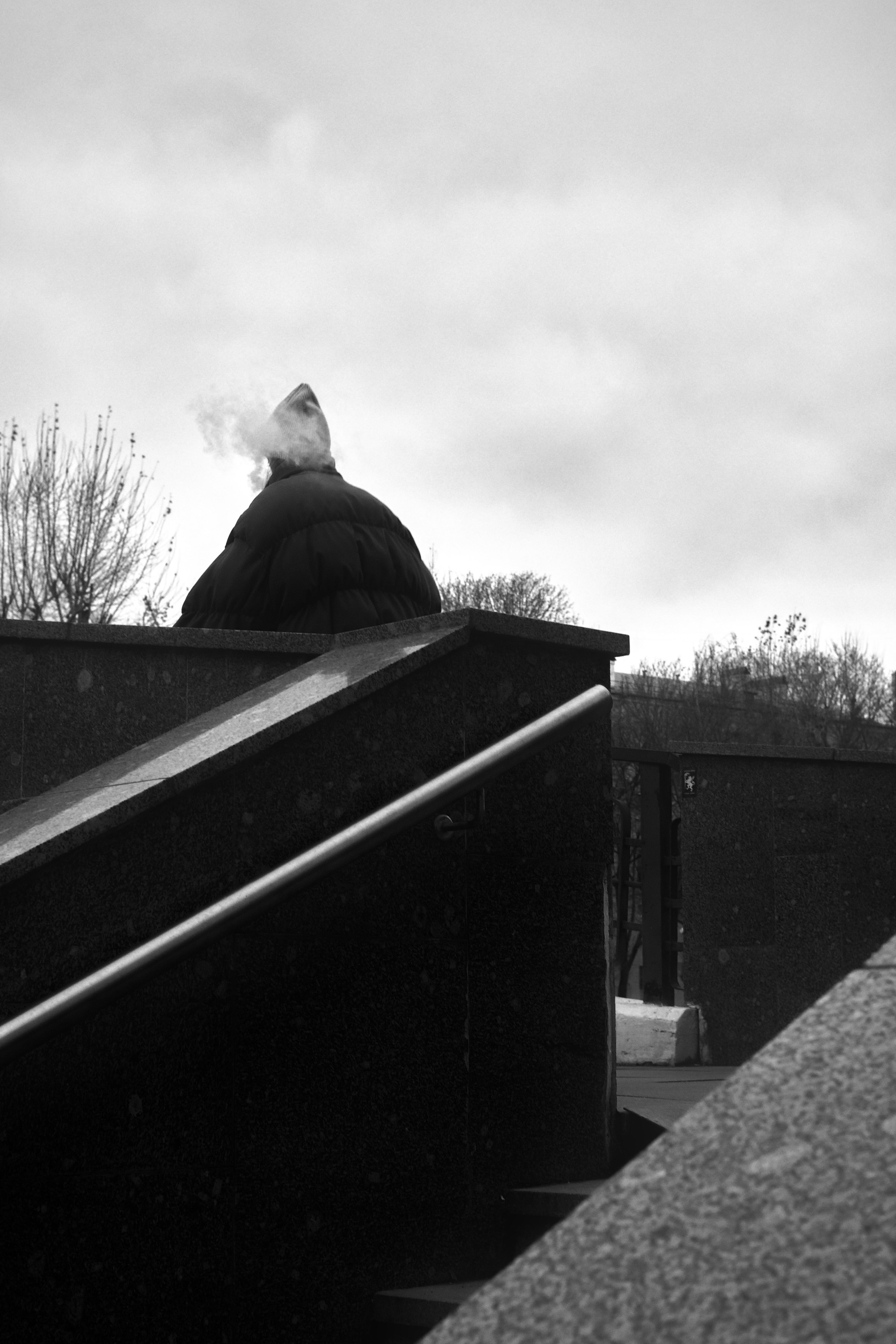 Человек и облако дыма на фоне облачного неба на мосту через водоотводный канал в Москве