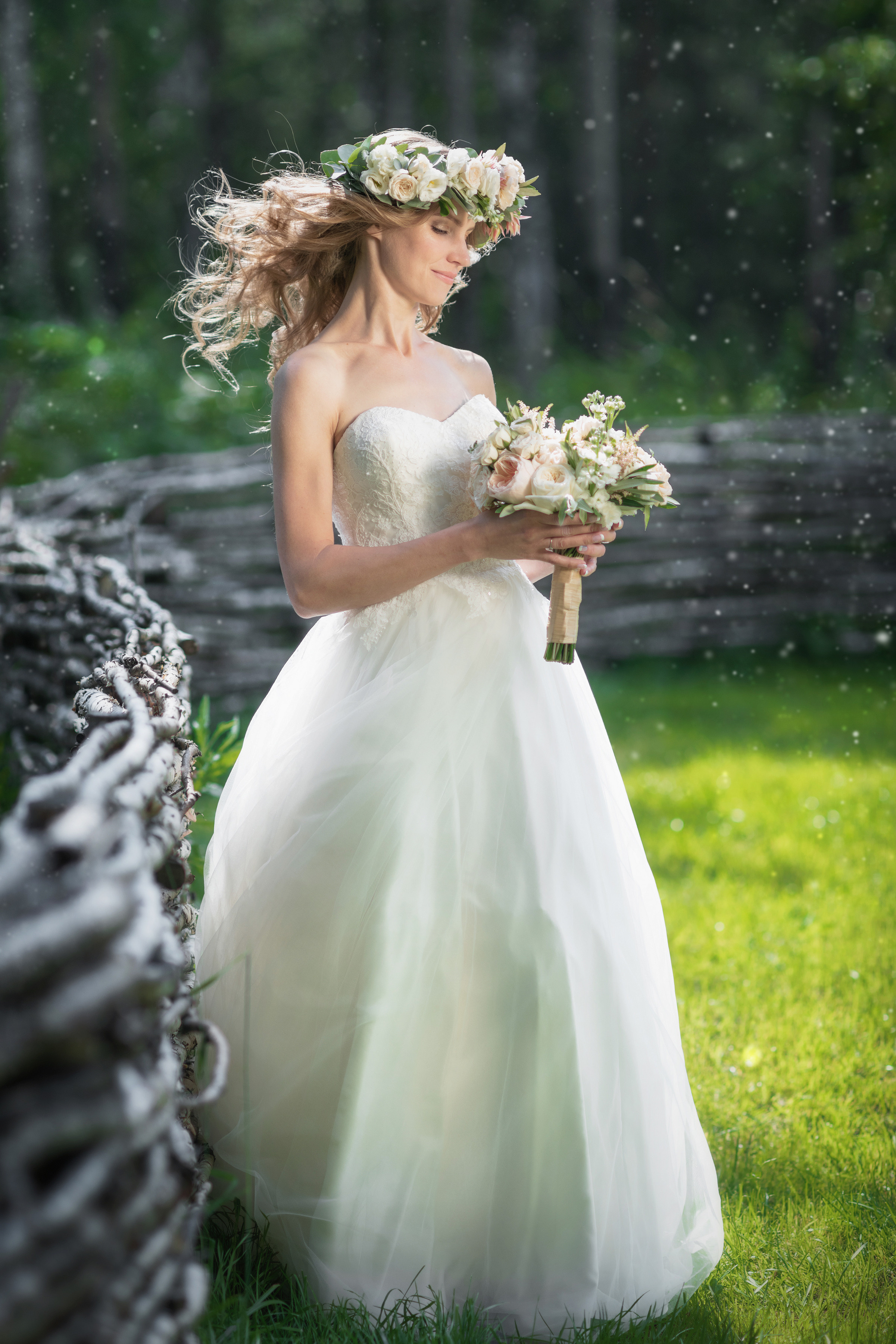 невеста с букетом и венком на голове стоит около забора