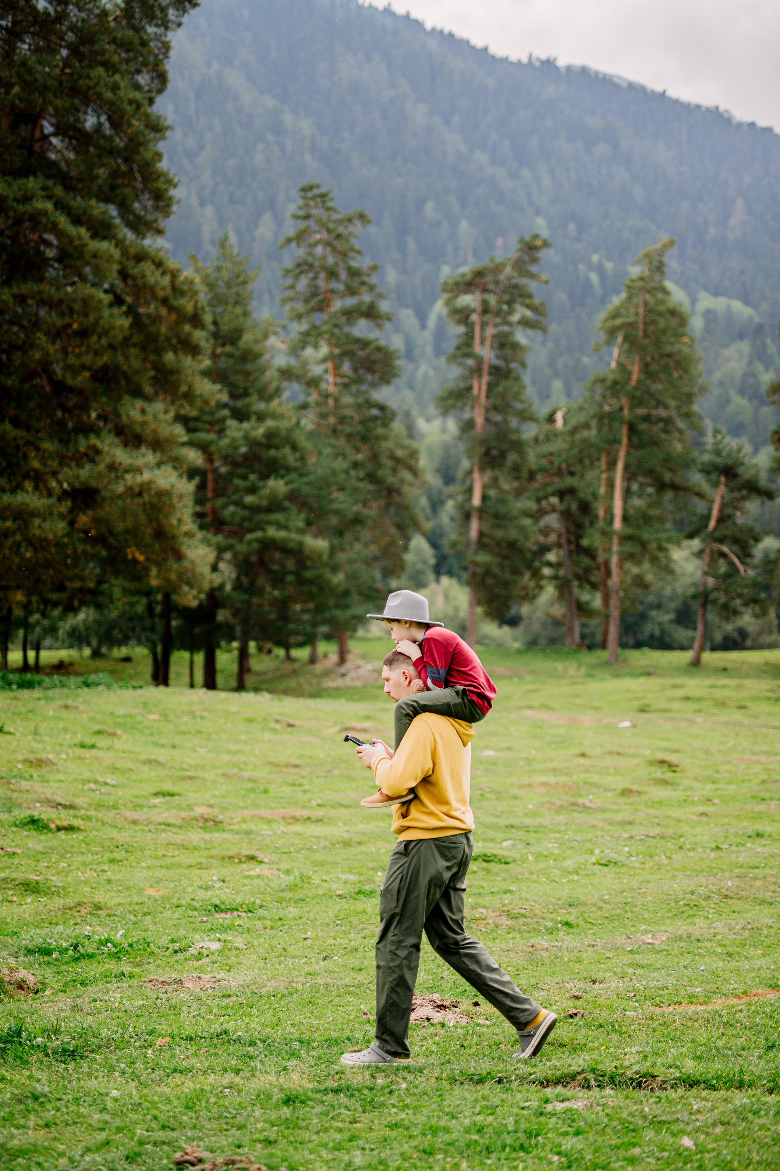 Архыз, горы, лес, семейная съемка в горах, Выездная съемка, фотограф на выезд, семейный фотограф в Астрахани, семейный фотограф,  портрет отца с сыном, отец с сыном гуляет в горах, сын сидит на плечах отца.