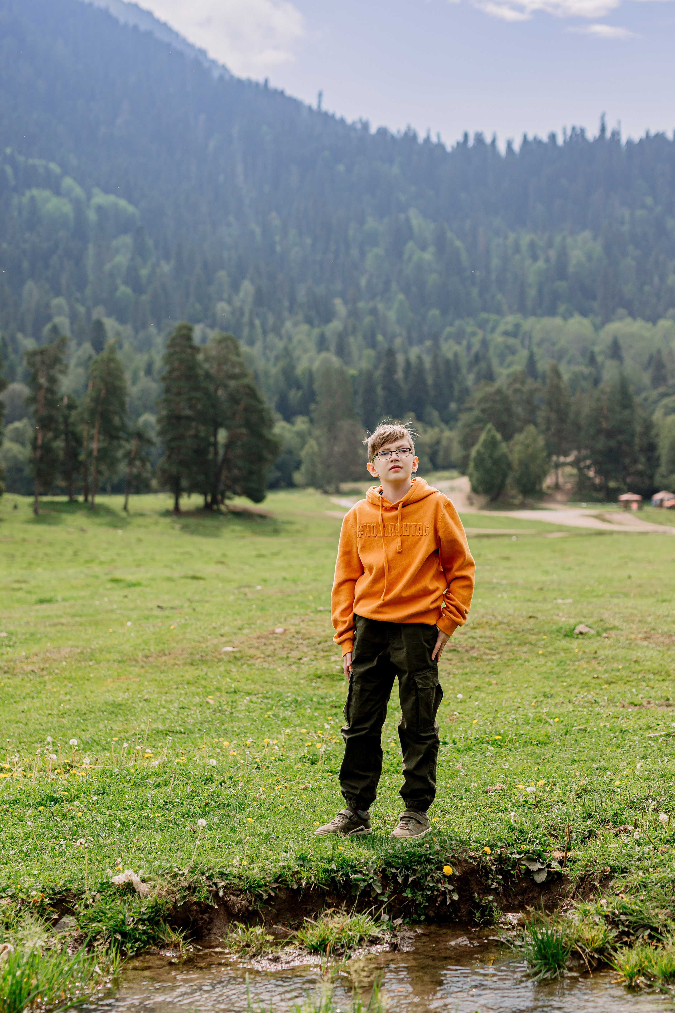 Архыз, горы, лес, семейная съемка в горах, Выездная съемка, фотограф на выезд, семейный фотограф в Астрахани, семейный фотограф, фотография мальчика на фоне гор в желтой толстовке