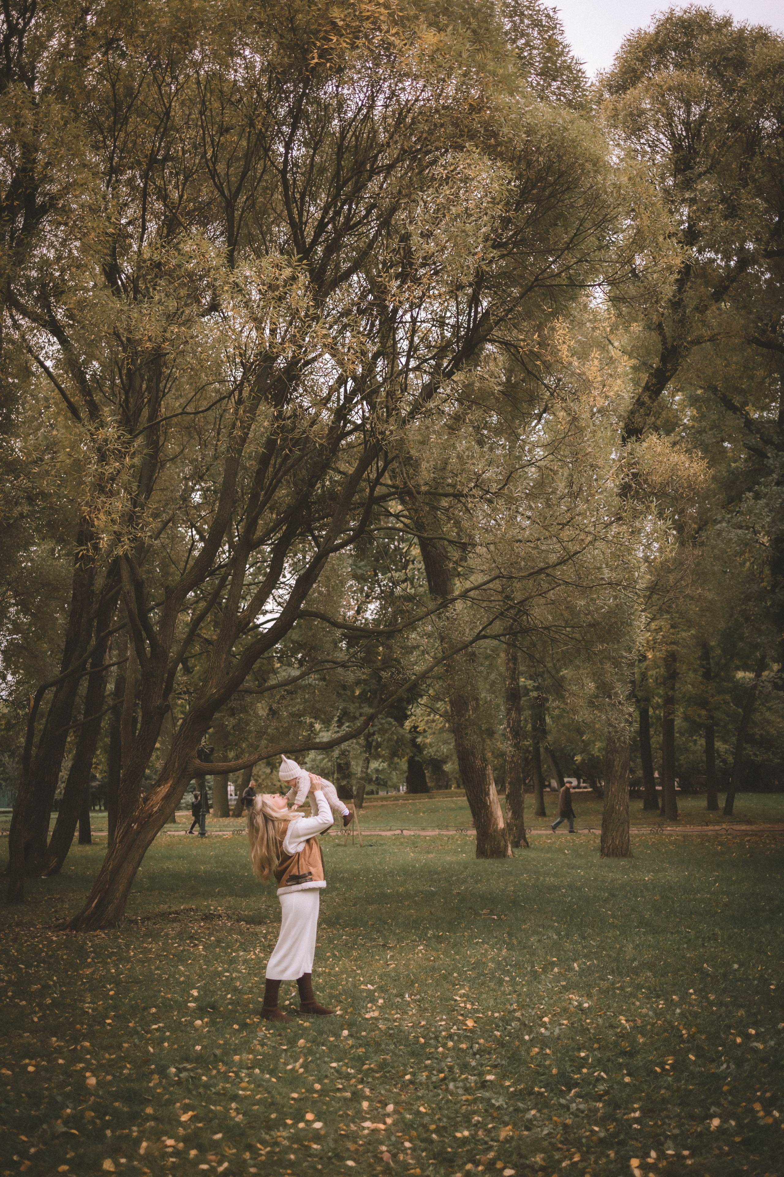 дальний кадр мамы с малышом в красивом парке