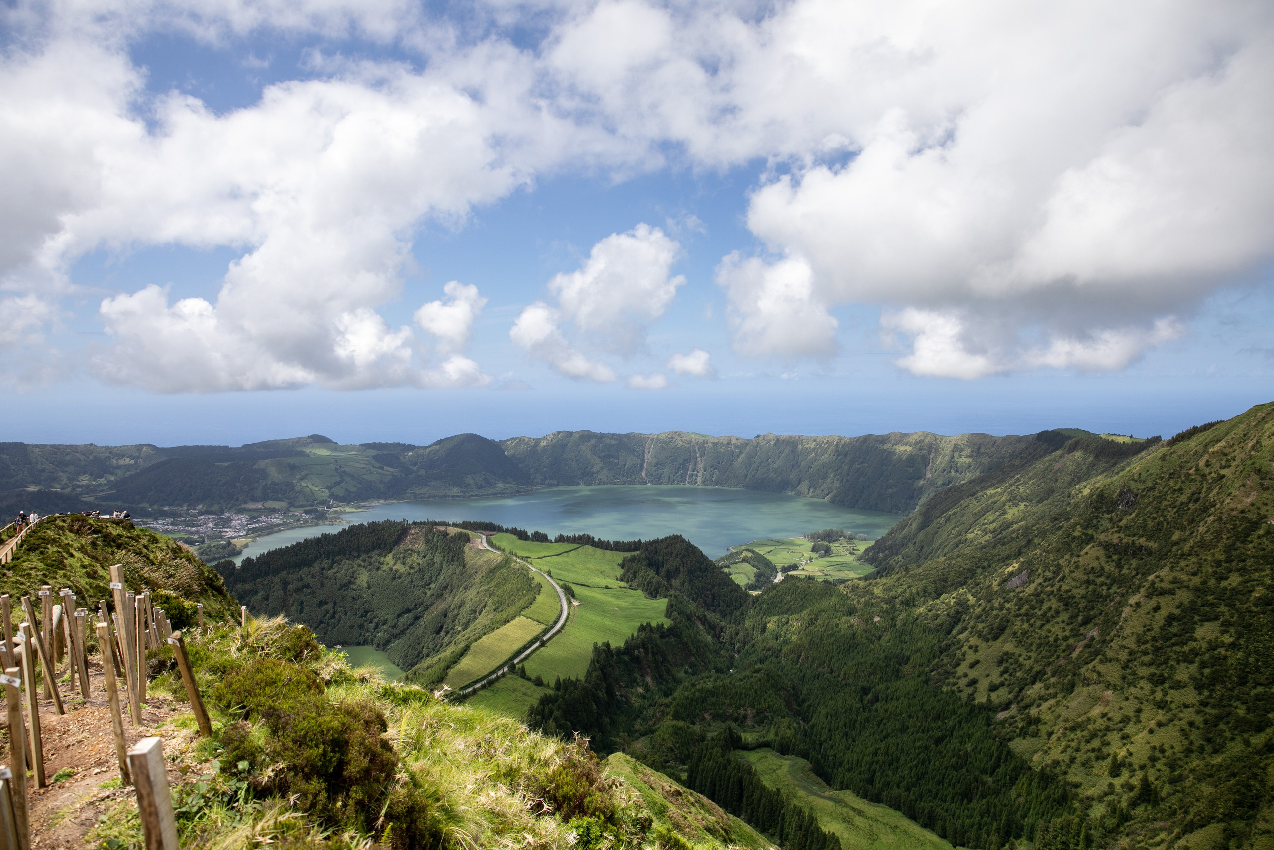 Women wander through the stunning landscapes of the Azores, surrounded by green hills, the ocean, and an open sky above