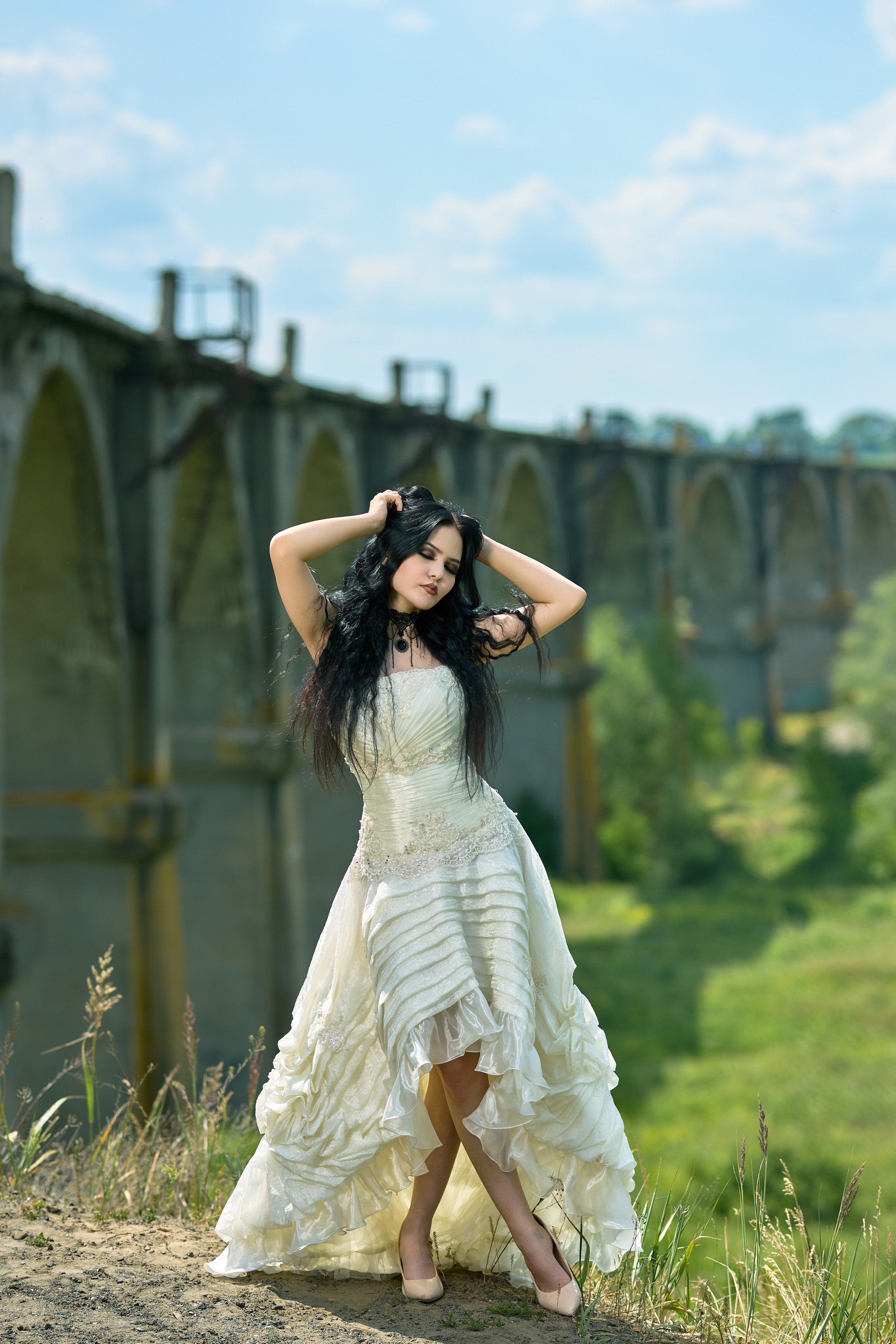 Девушка с черными волосами, в винтажном платье стоит на фоне мокринского моста