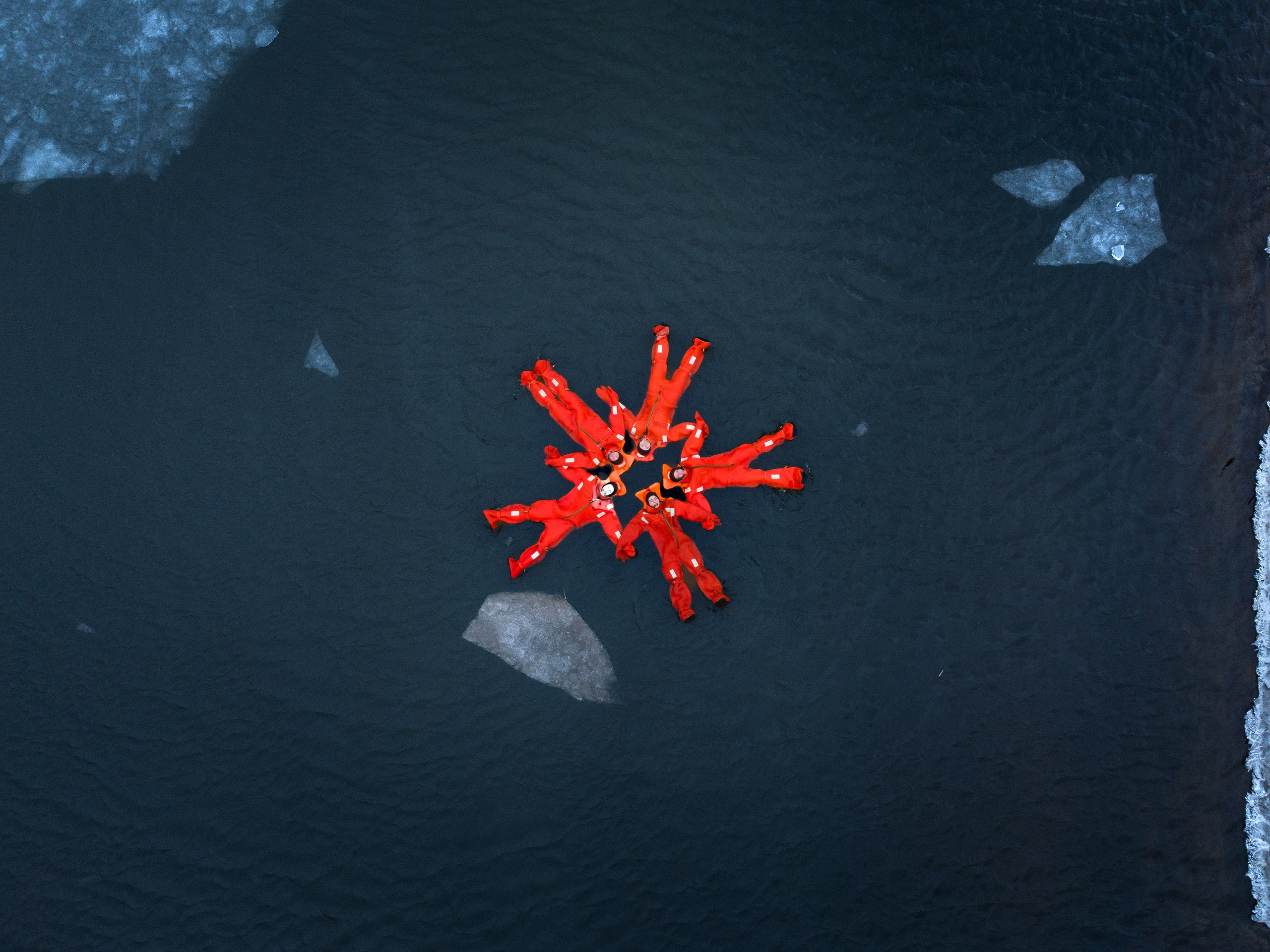 Люди купаются среди льдин, в спасательных оранжевых термо костюмах, айс флоатинг Ярославль