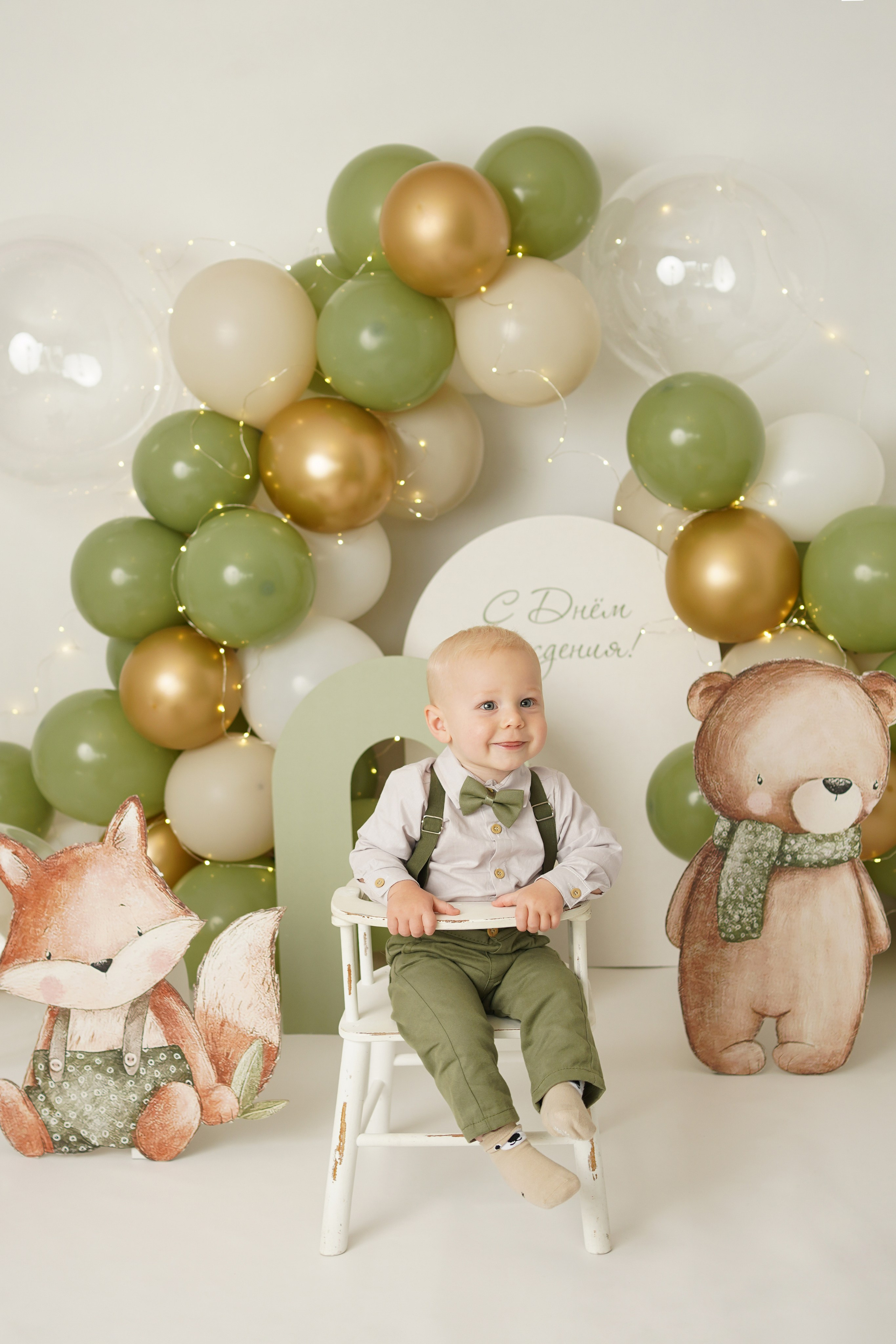 На фото малыш сидит на стульчике на праздновании своего первого года.