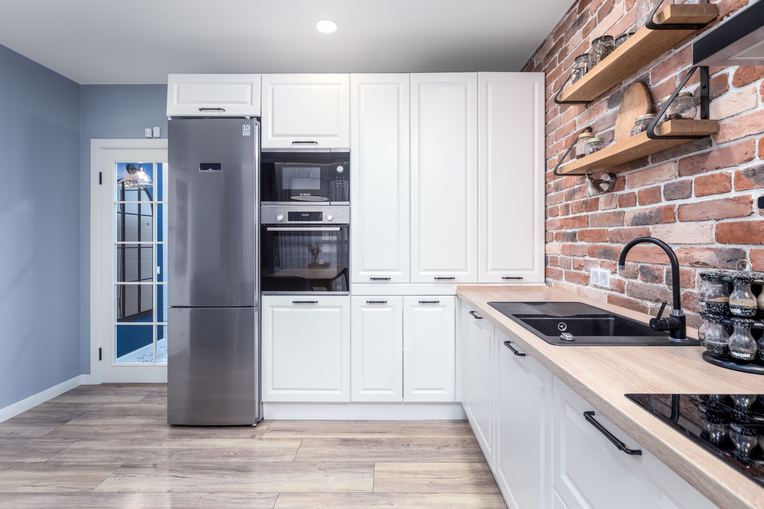 Интерьер кухни - холодильник, духовой шкаф, микроволновая печь и раковина с посудомойкой