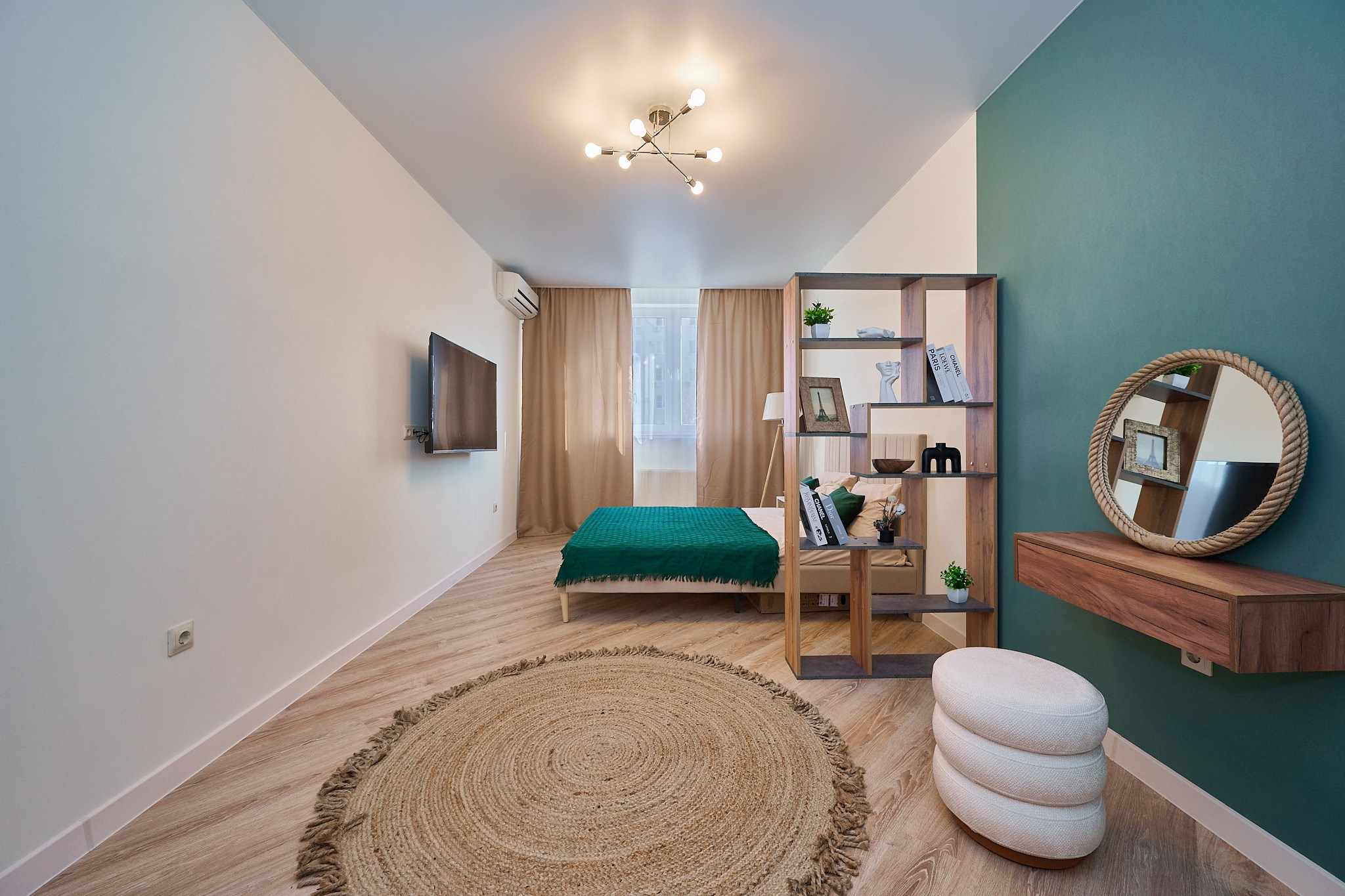 белые стены белые оттенки одна бирюзовая стена круглый светлый ковер с бежевыми шторами  и деревянной кроватью 