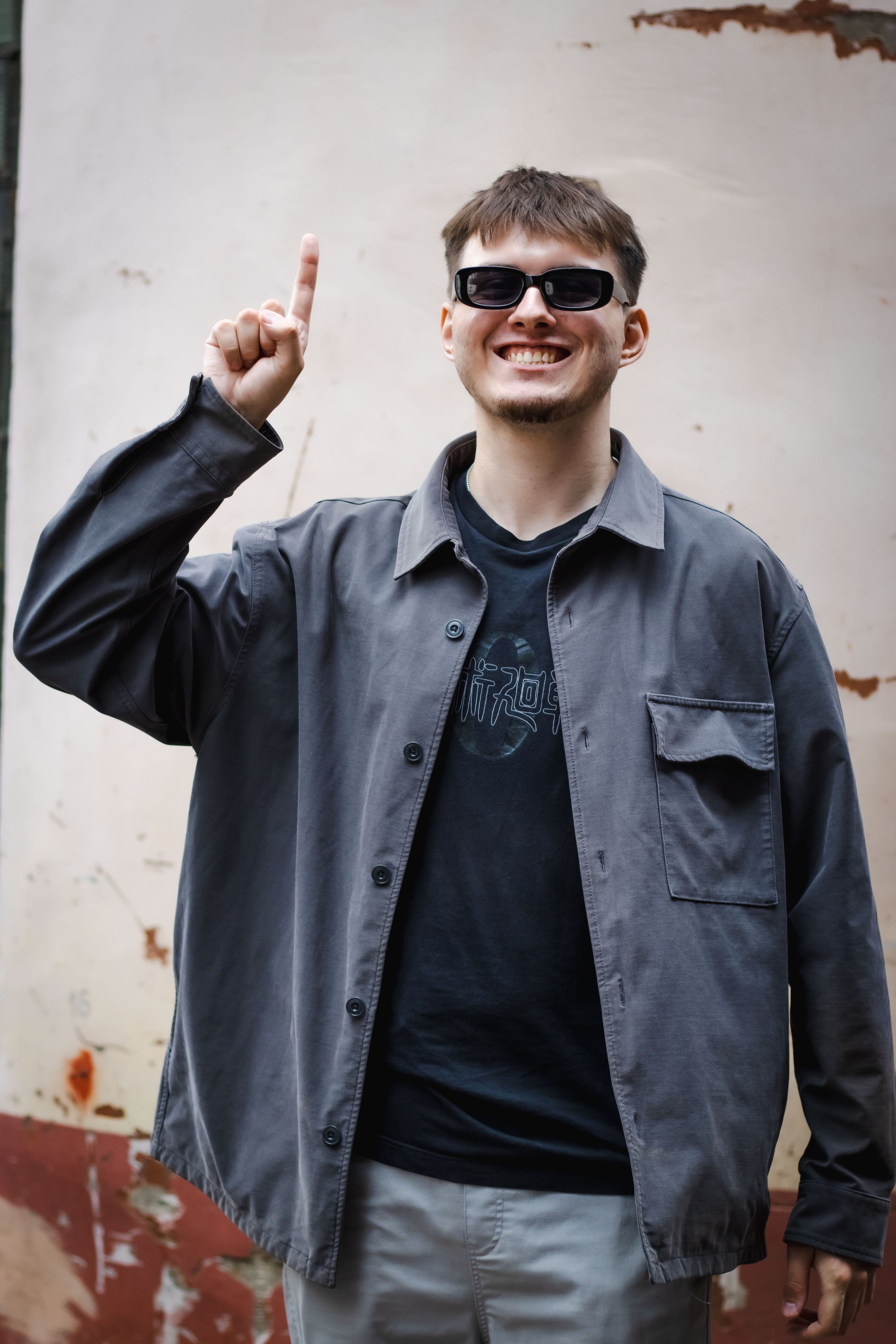 парень с широкой улыбкой и указательным пальцем в верх