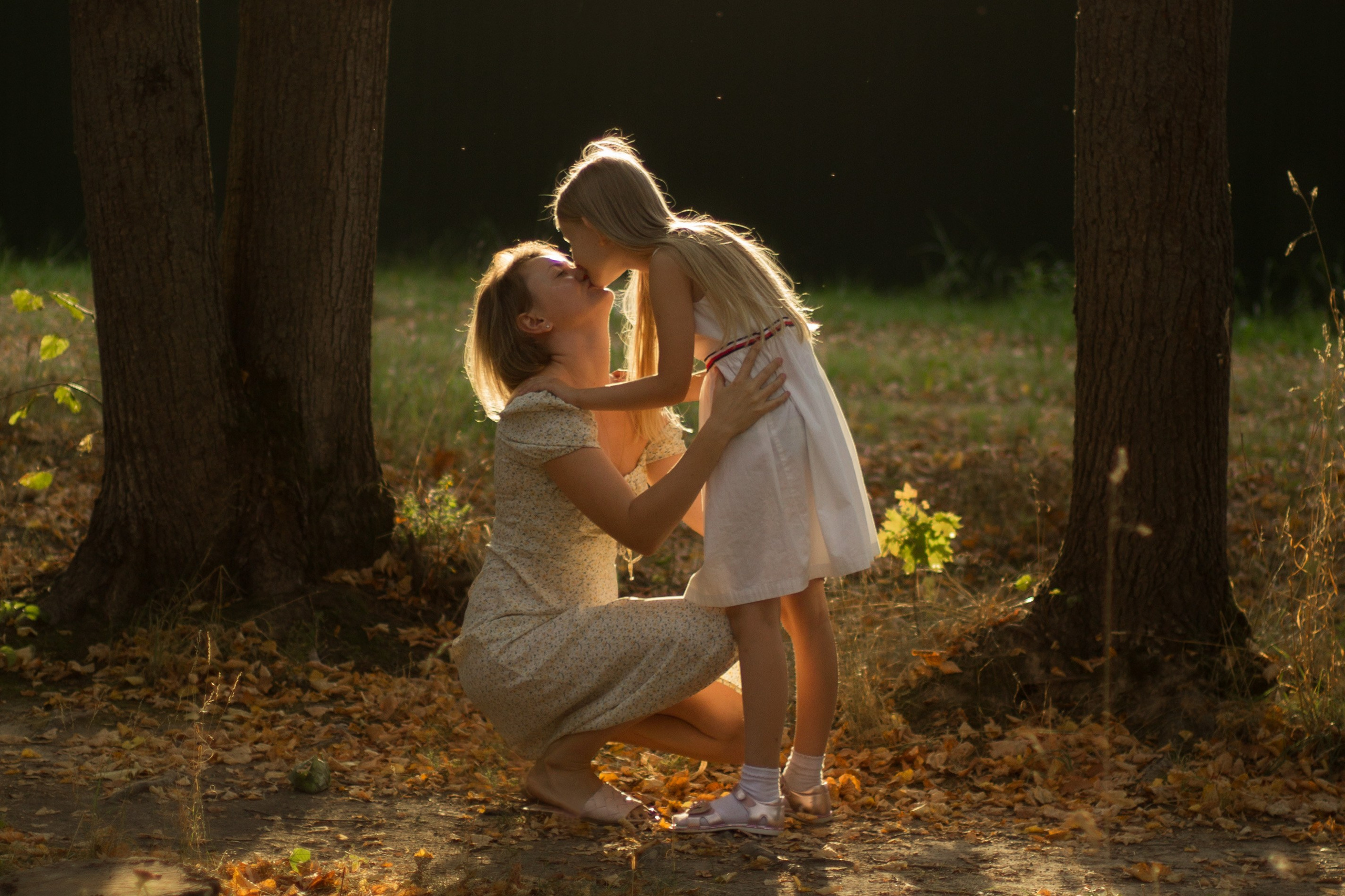 Фотография мамы и дочки в контровом свете, мама целует дочку