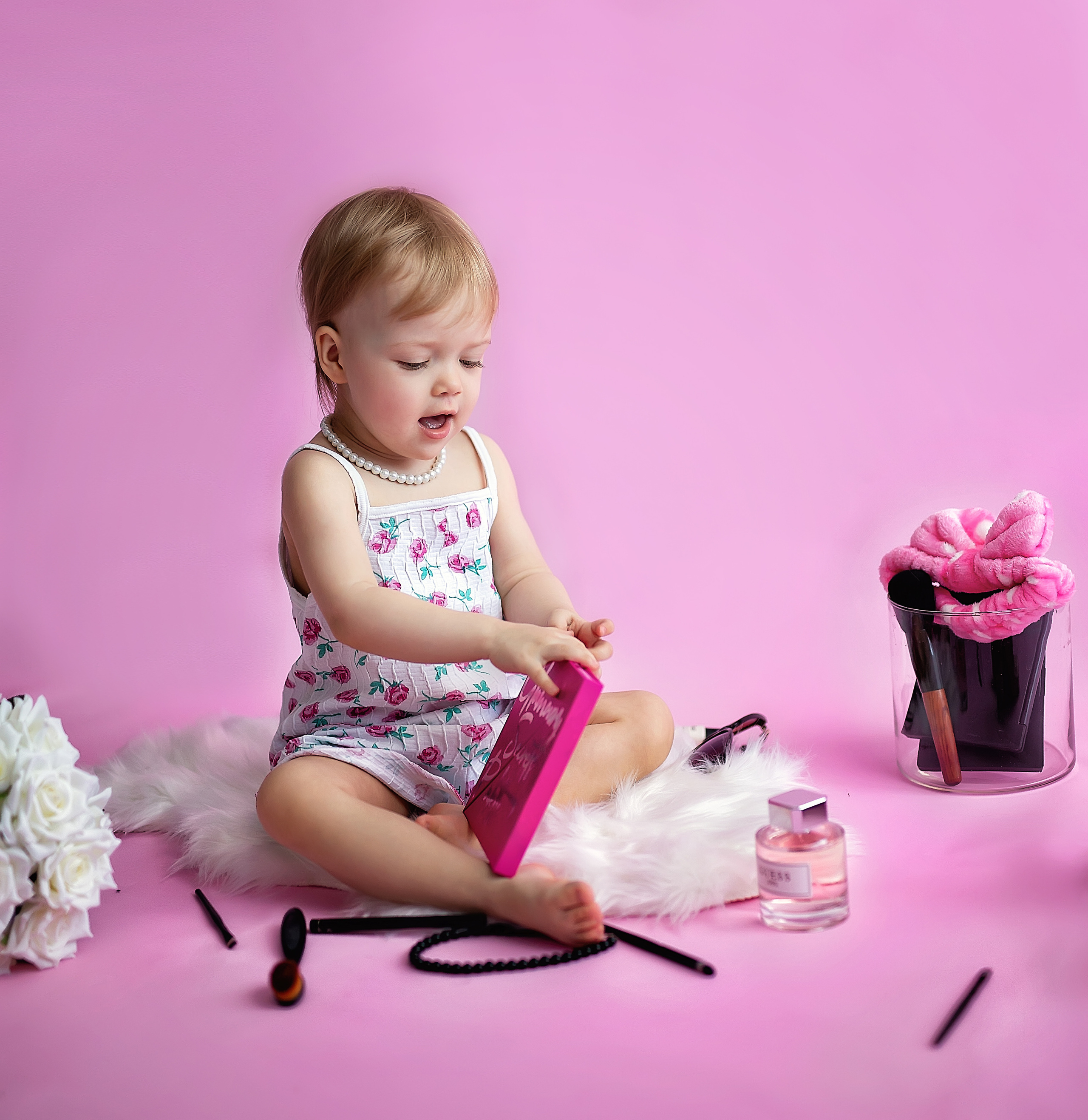 Модница открывает тени и приятно удивляется она сидит на розовом фоне с бусами.