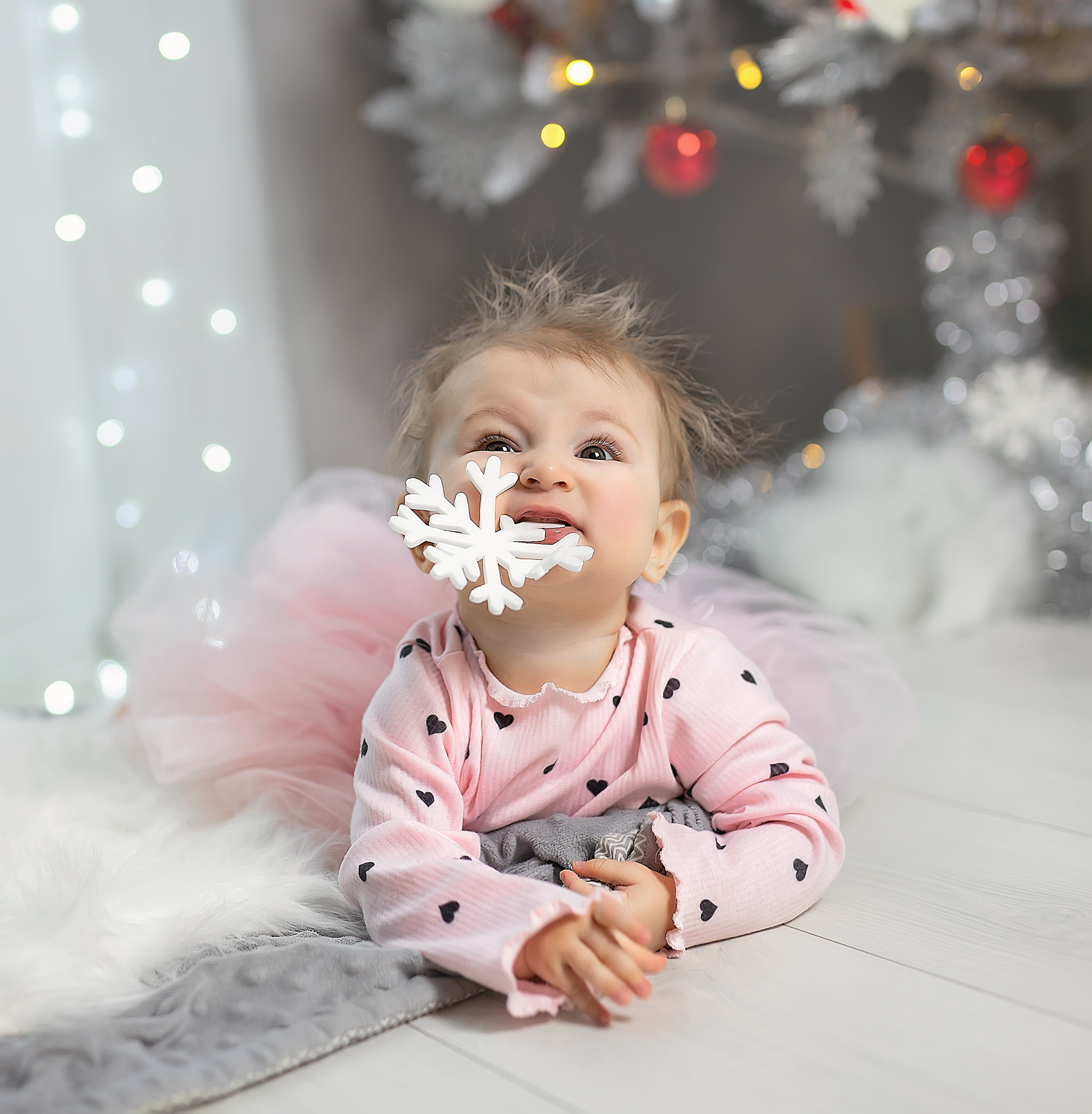 Очень смешная маленькая девочка держит снежинку в зубах.