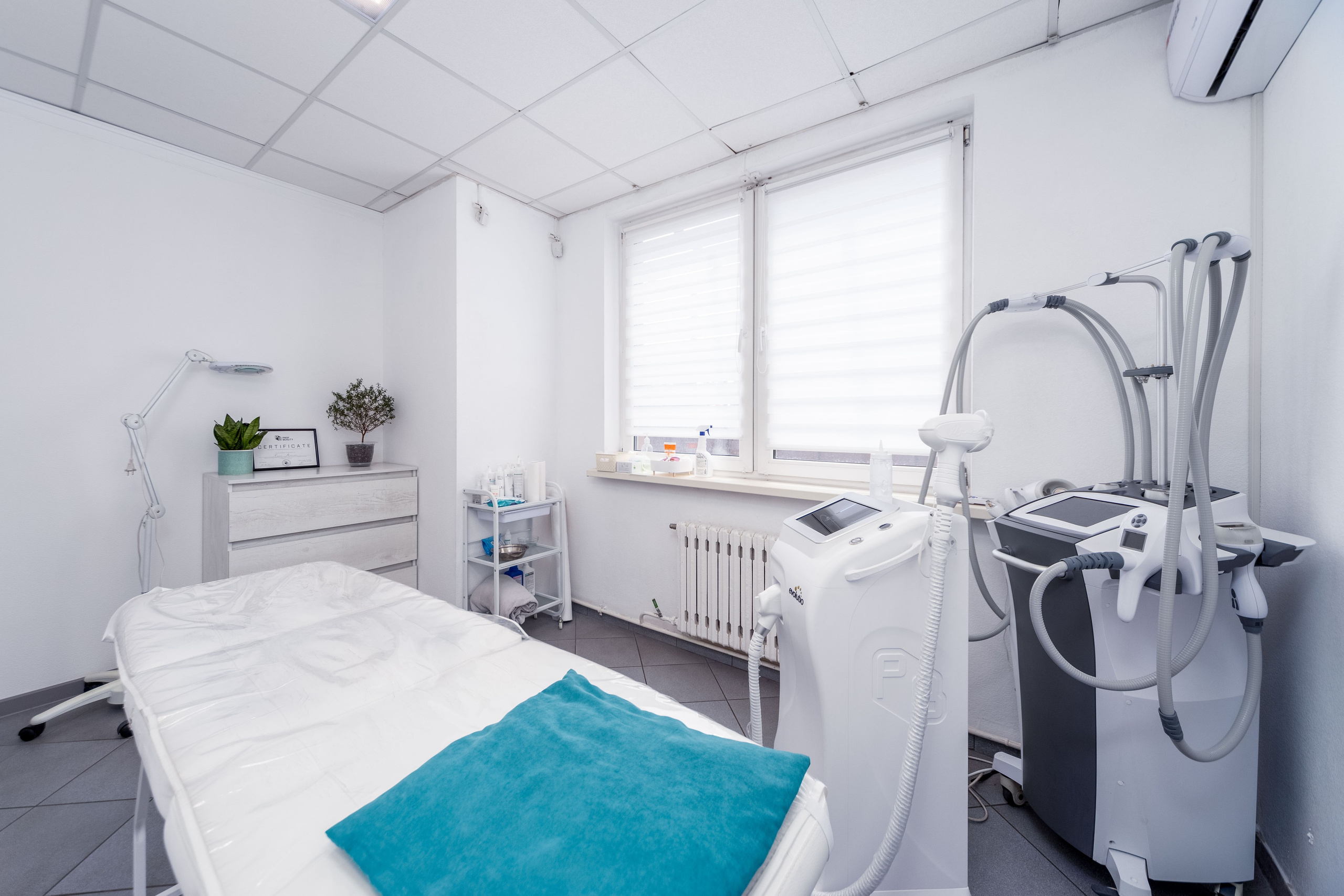 Кушетка, медицинское оборудование и большое видовое окно в косметическом кабинете