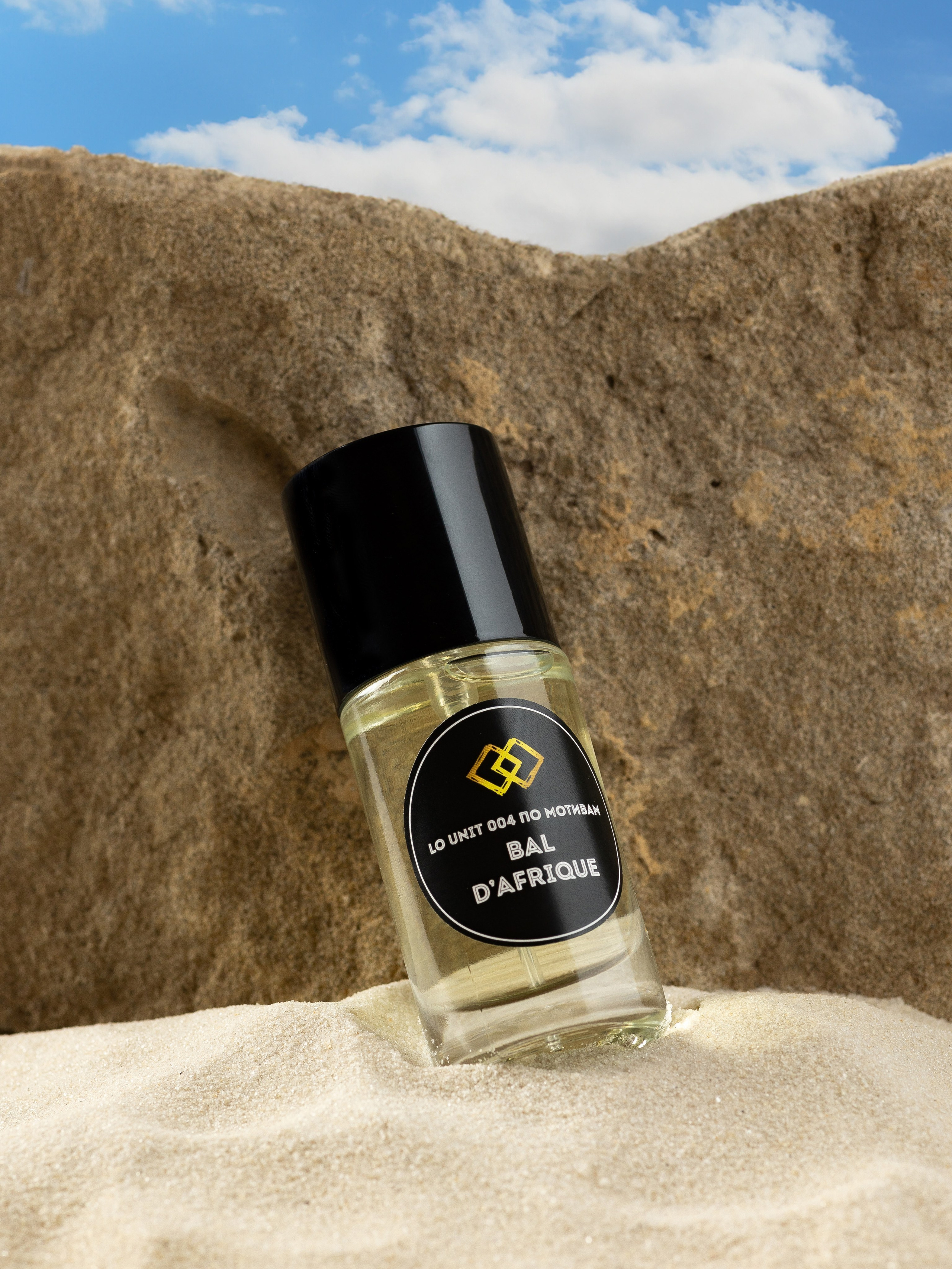 Флакон духов на белом песке на камне на фоне голубого неба, предметная съемка для маркетплейсов