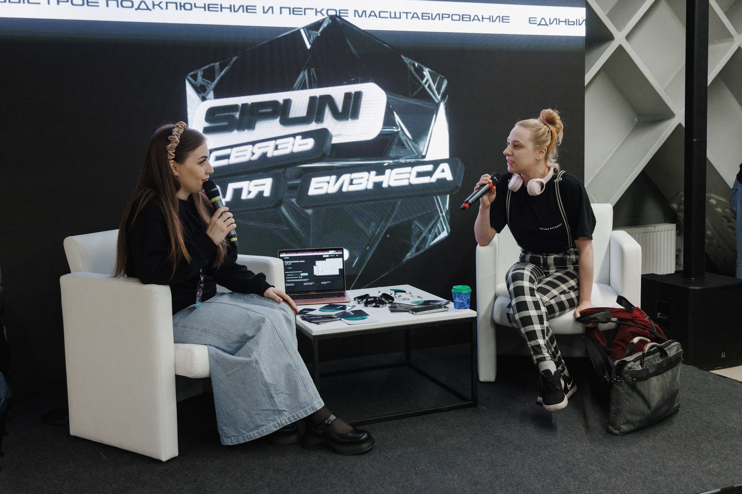 Сотрудники общаются с гостями на корпоративном стенде во время выставки.